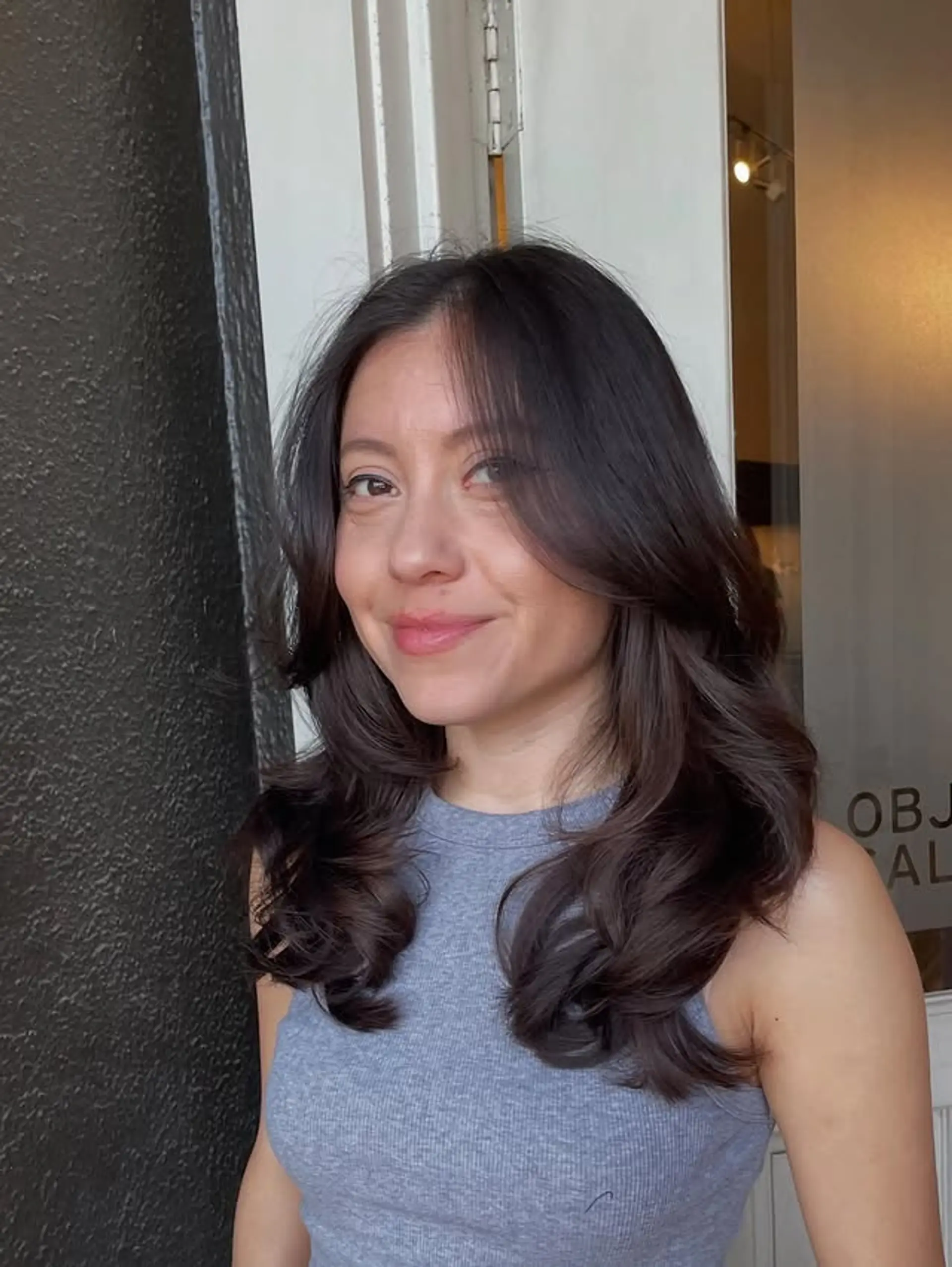 This is a medium-length hairstyle with long layers and soft curtain bangs. 1