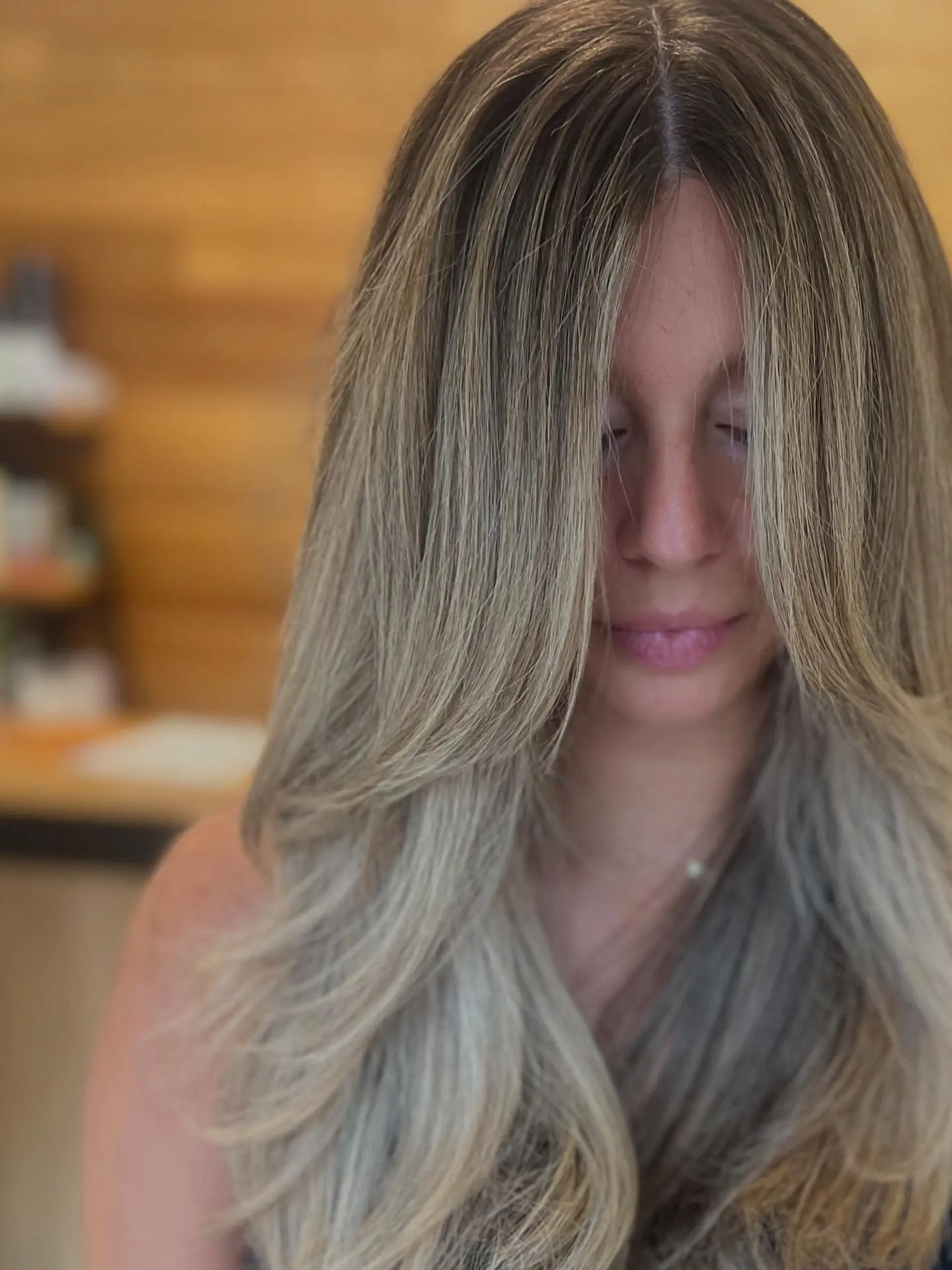Long ash blonde balayage with voluminous face-framing curtain layers and smooth, softly curled ends. 1
