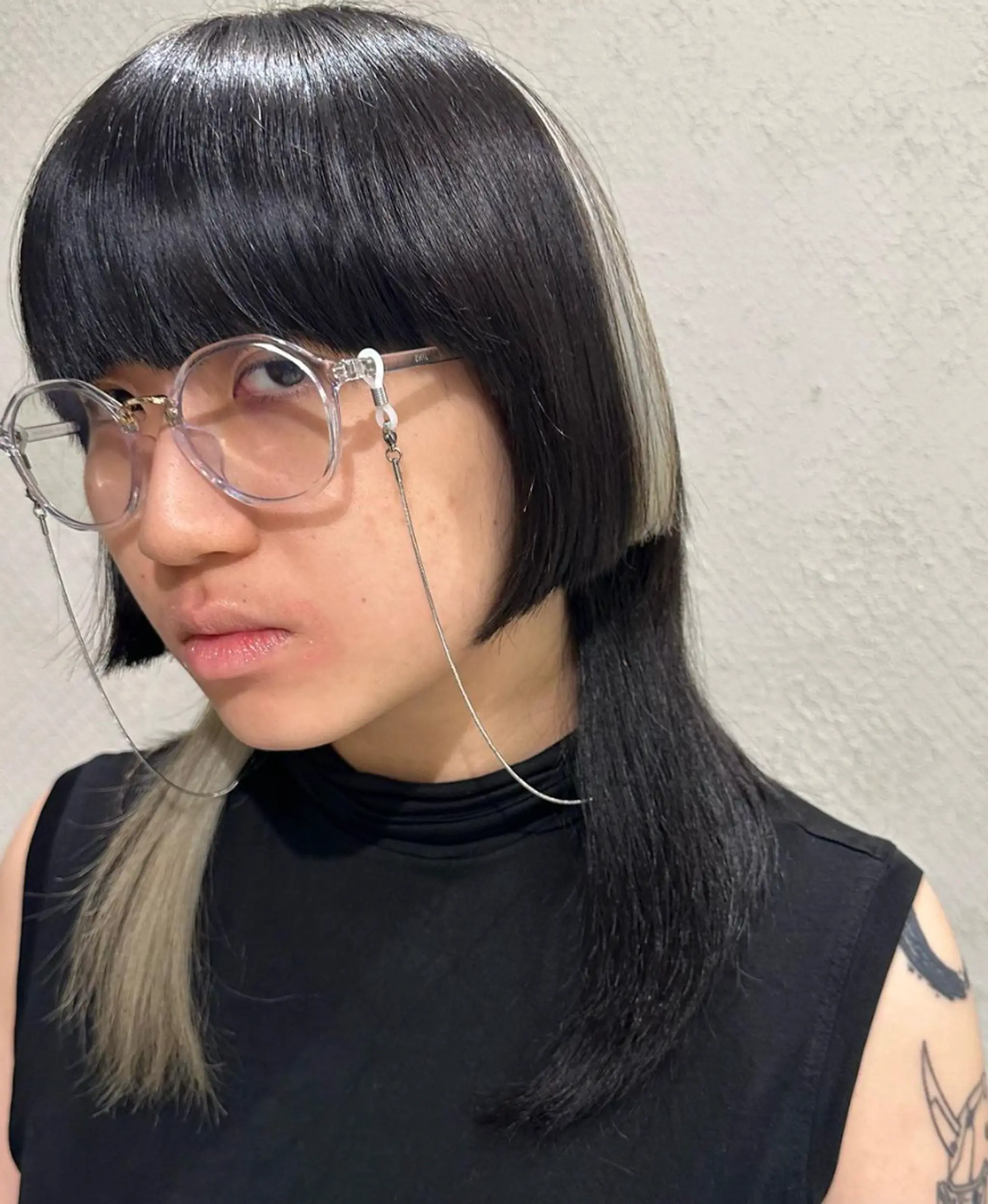 An asymmetrical style with sleek, straight hair featuring a blunt fringe and contrasting black and platinum hues, creating a dynamic and modern appearance.