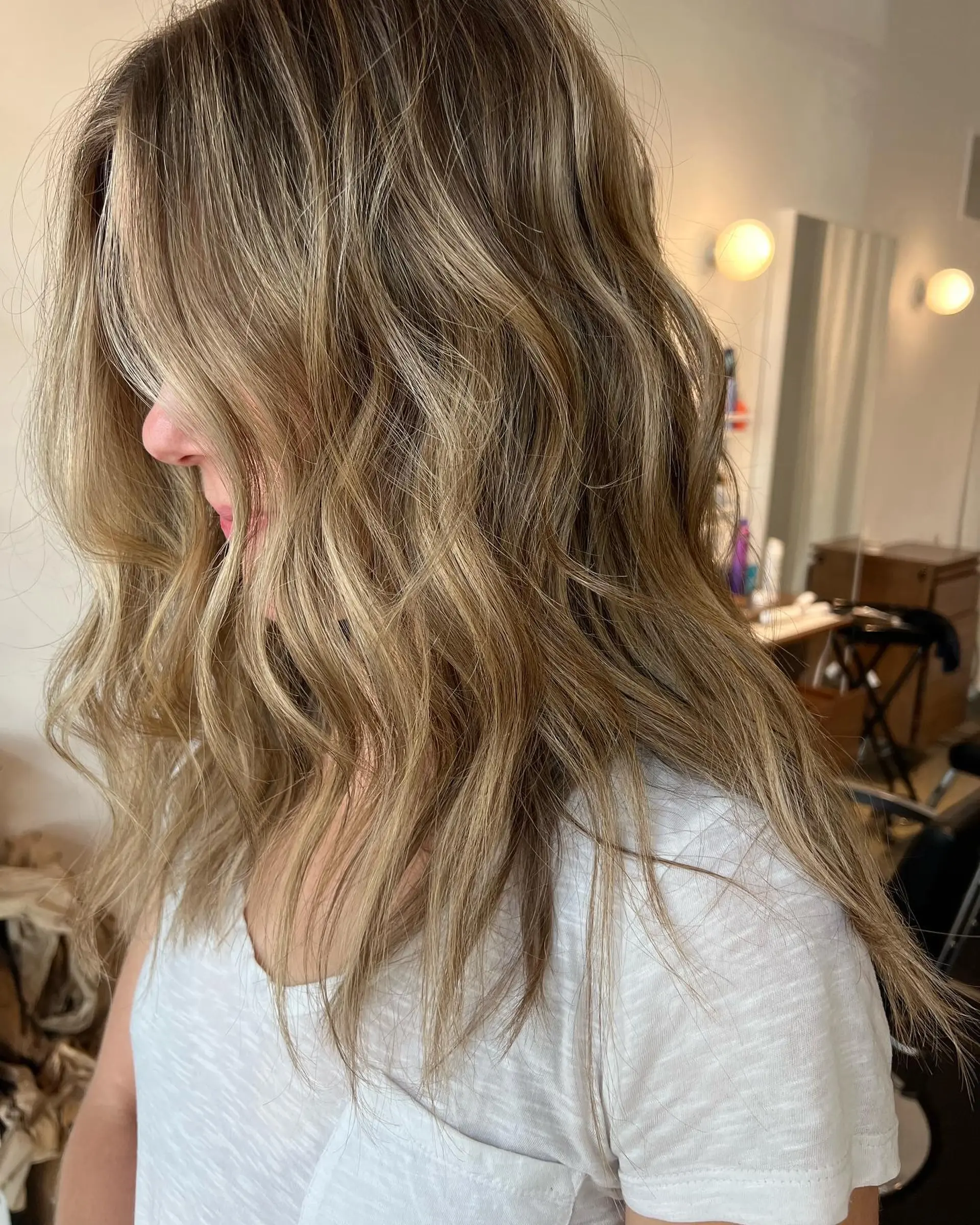 Long dimensional warm blonde hair styled with relaxed, textured beach waves. 1