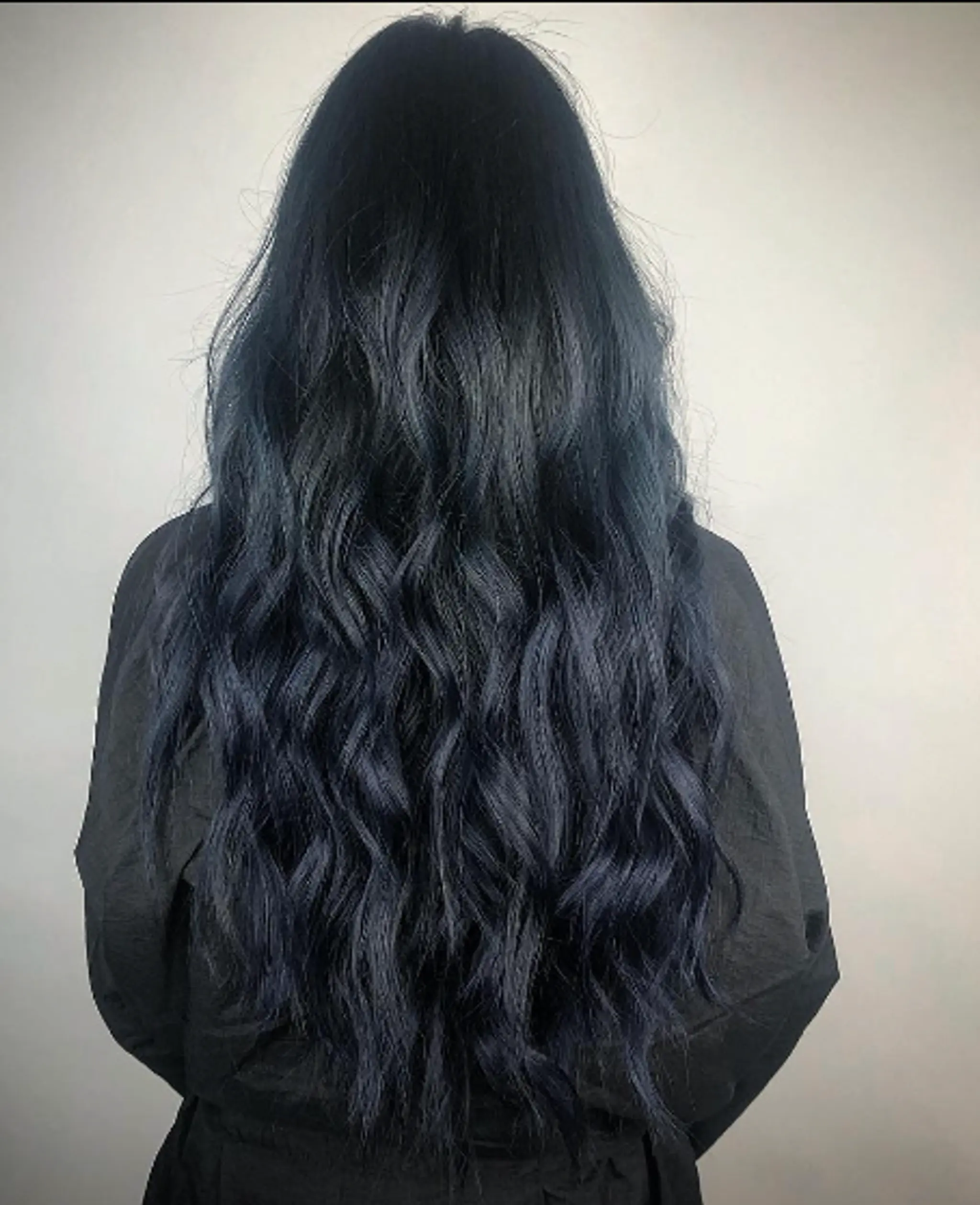 Very long, wavy hair with a deep black base color and subtle blue undertones, loose waves, and a smooth, shiny texture.
