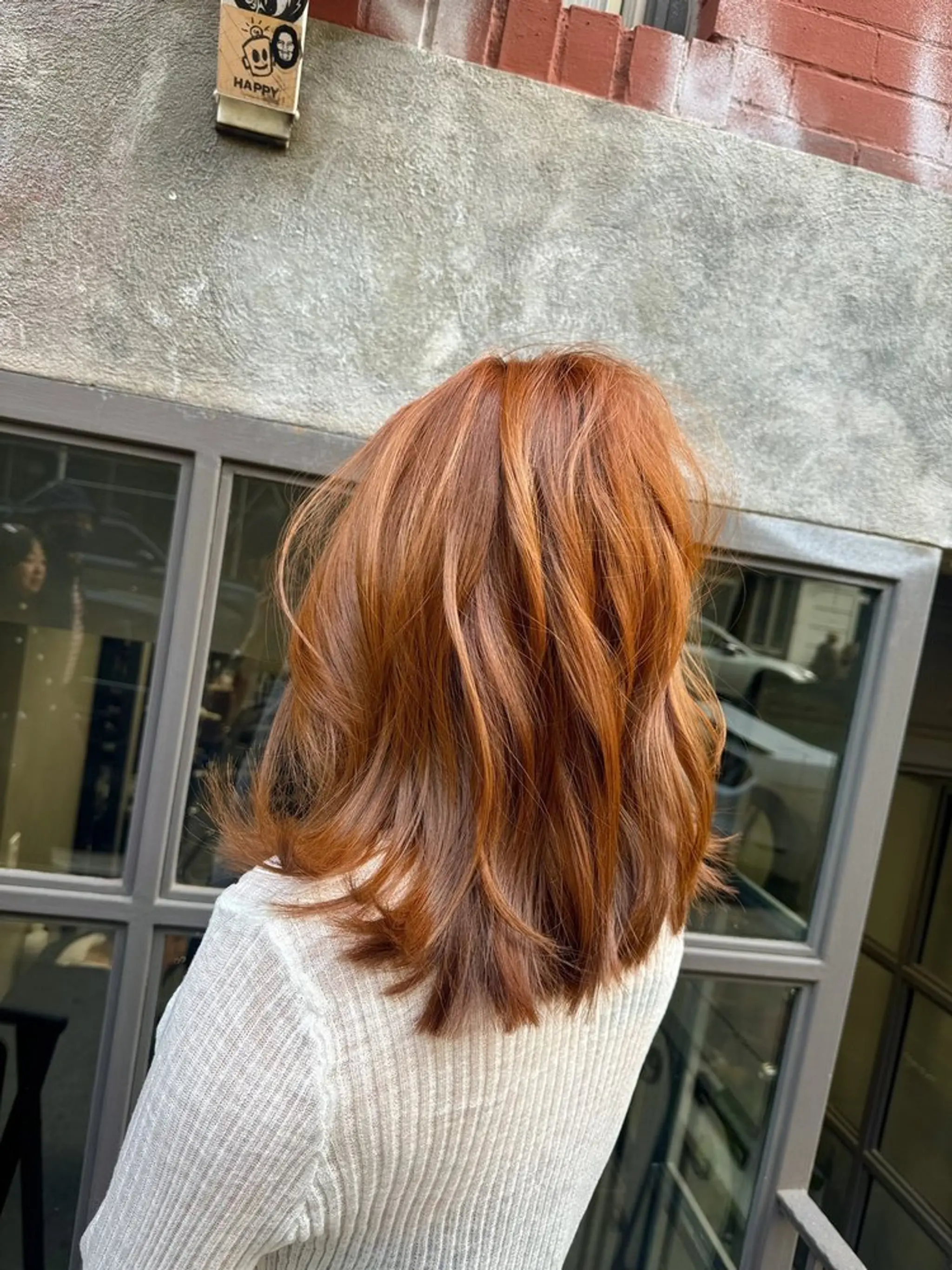 A medium-length, wavy hairstyle with vibrant copper and auburn tones. The hair flows down to the shoulders in voluminous waves with elegant layers adding body and movement.