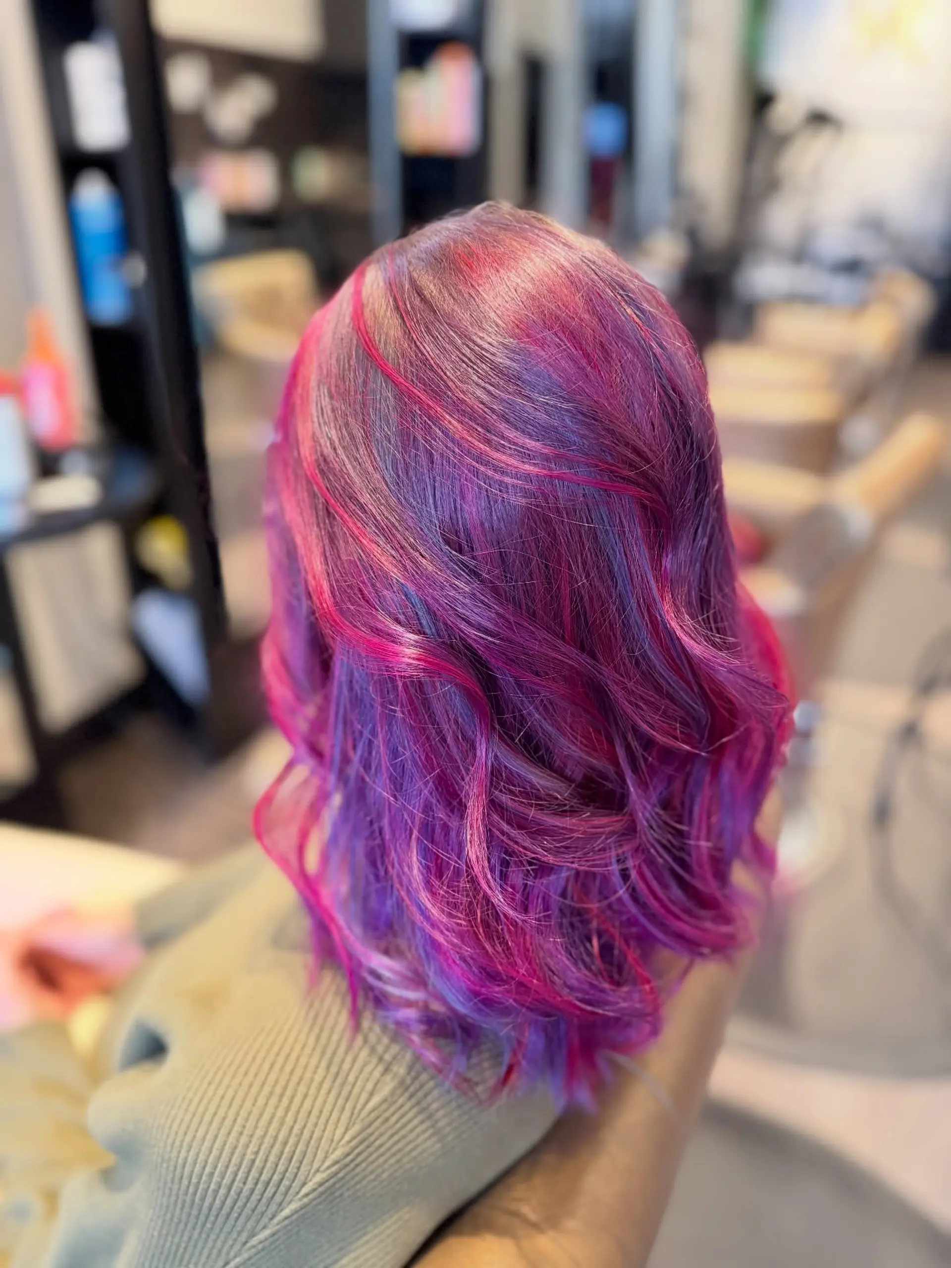 Shoulder-length textured lob featuring vibrant multi-tonal vivid shades of magenta, violet, and electric blue styled in soft waves. 1