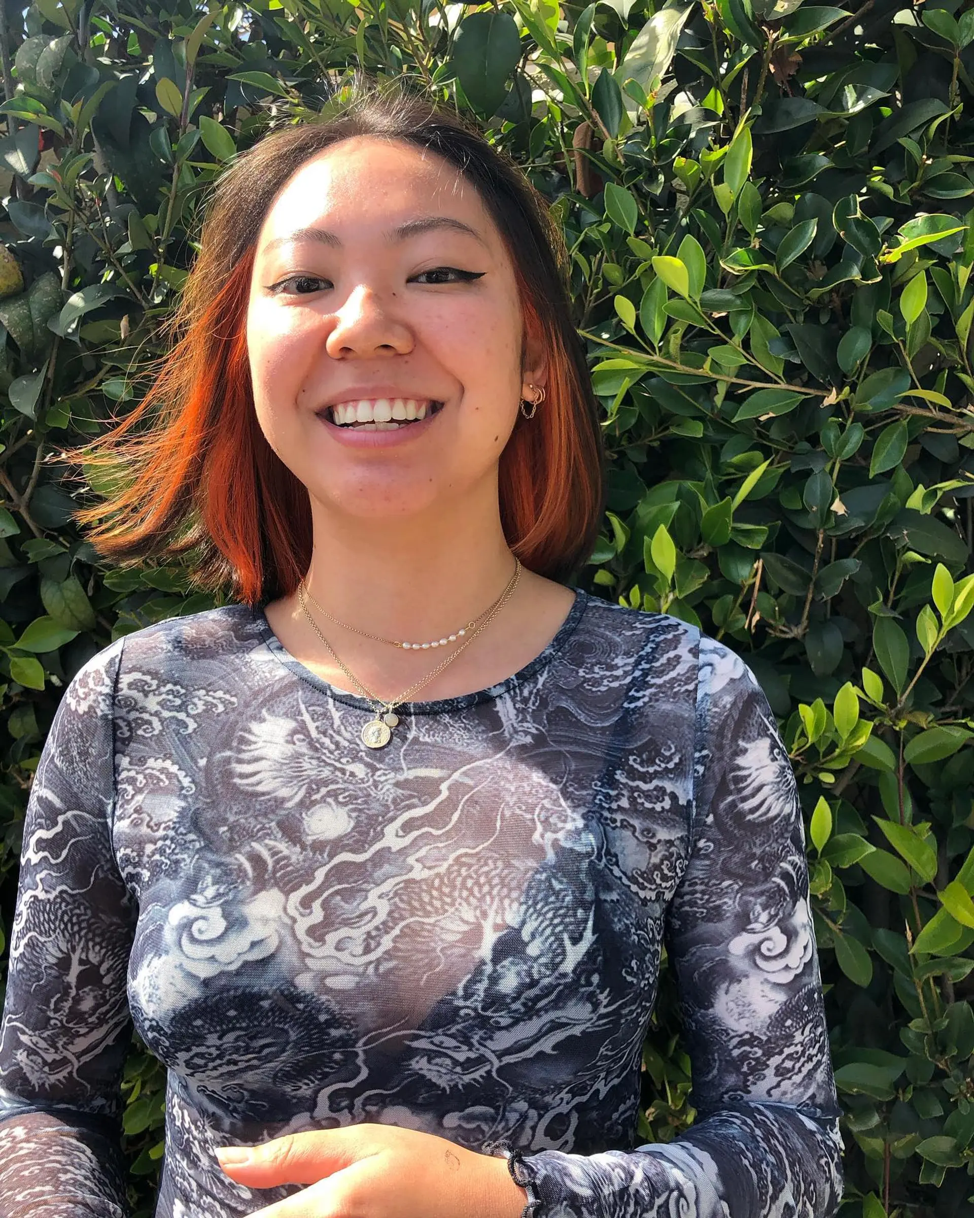 A straight short bob haircut featuring vibrant copper-orange peekaboo inner color beneath a dark brown overlay. 1