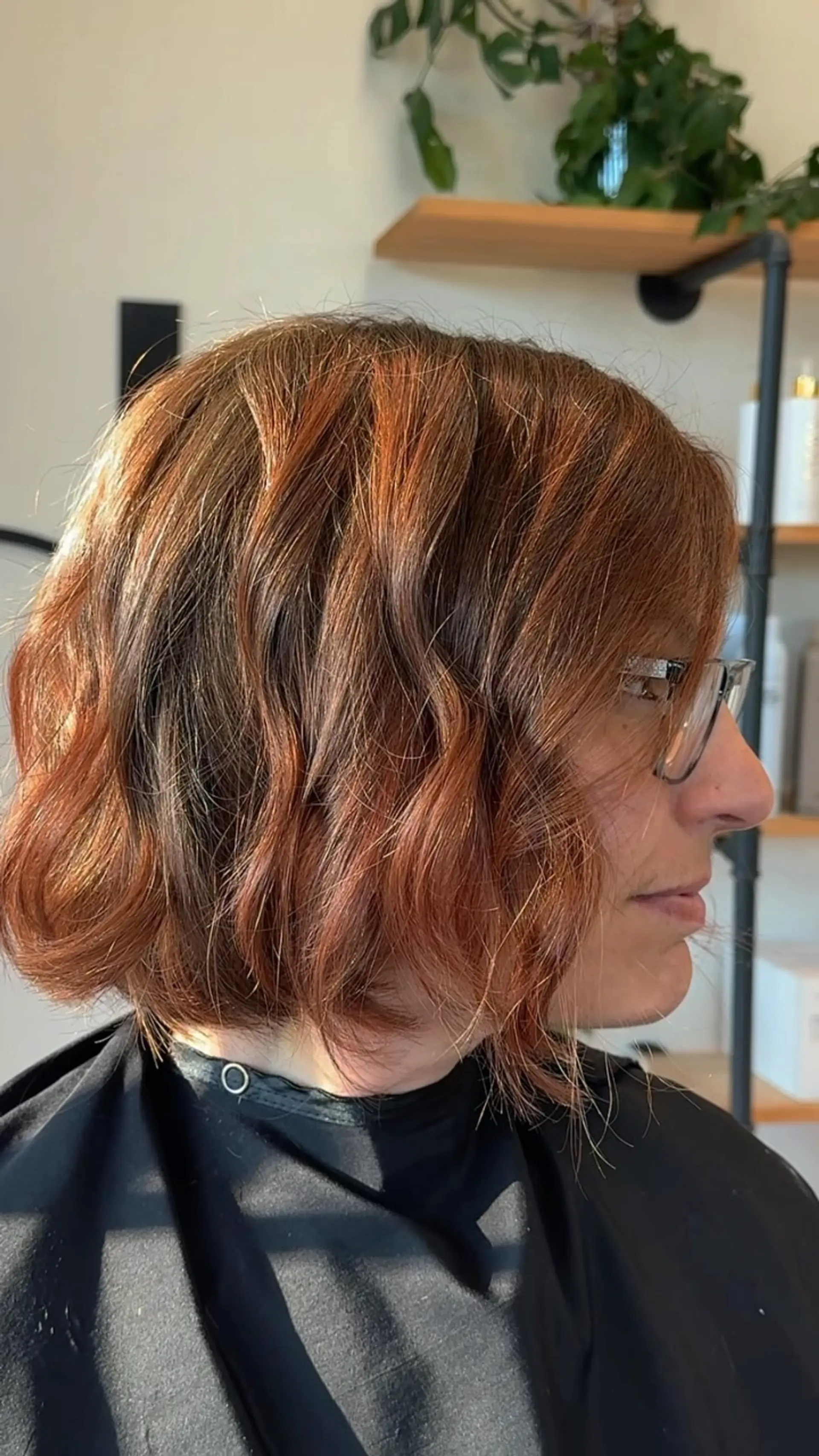 A chin-length textured bob styled with loose waves and multidimensional auburn-copper color. 1