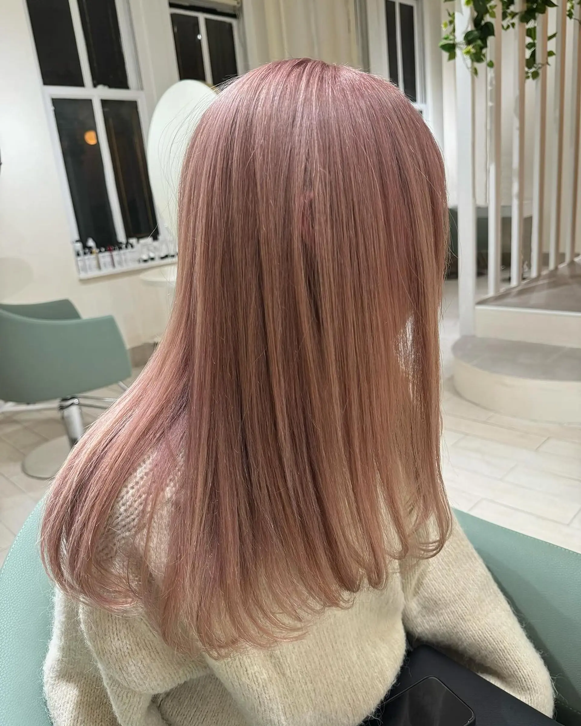 Smooth, straight medium-length hair in a sleek and glossy rose gold shade, featuring a soft pink hue. The hairstyle includes a side-part which allows the hair to drape naturally over the shoulders. 1