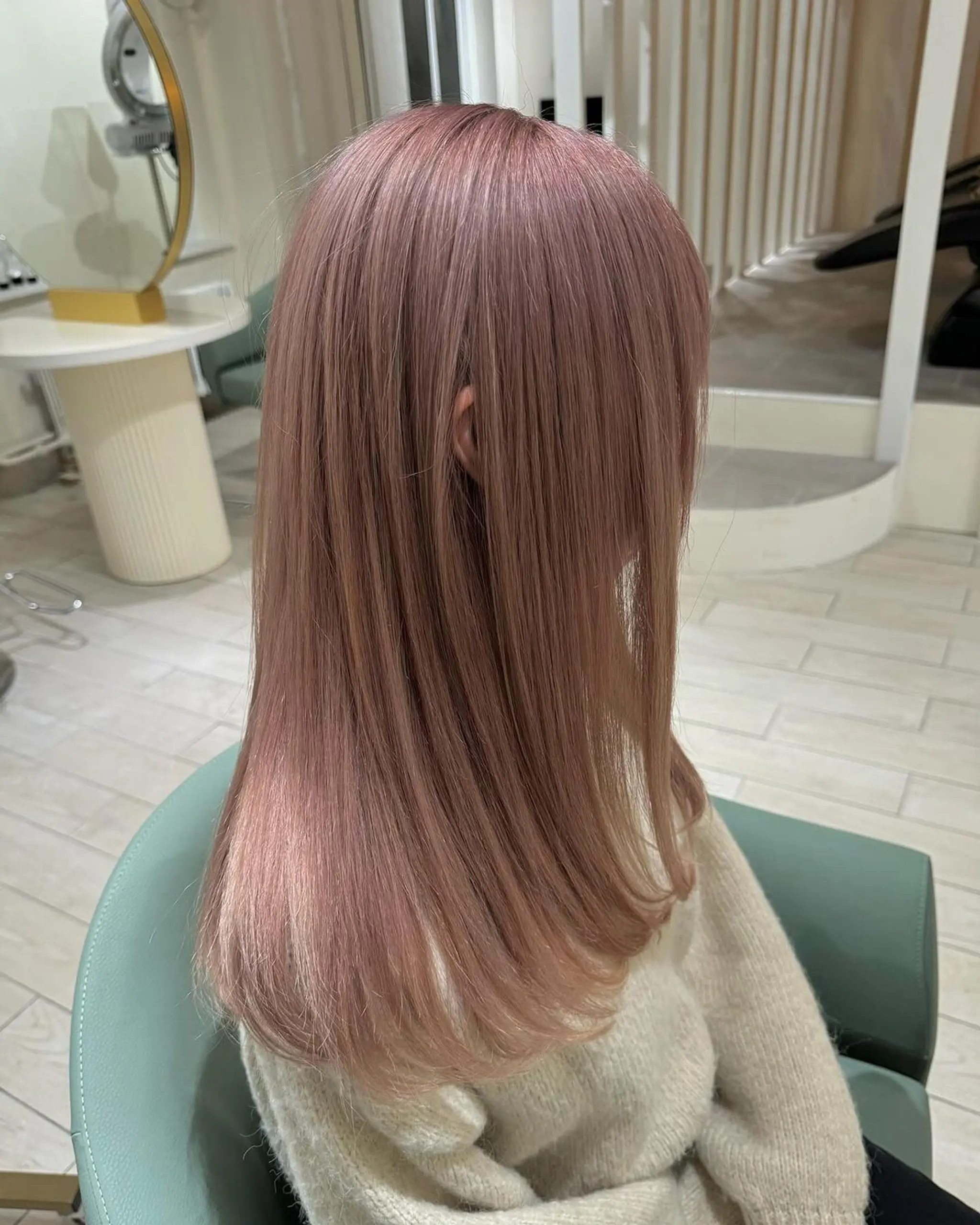Smooth, straight medium-length hair in a sleek and glossy rose gold shade, featuring a soft pink hue. The hairstyle includes a side-part which allows the hair to drape naturally over the shoulders. 3