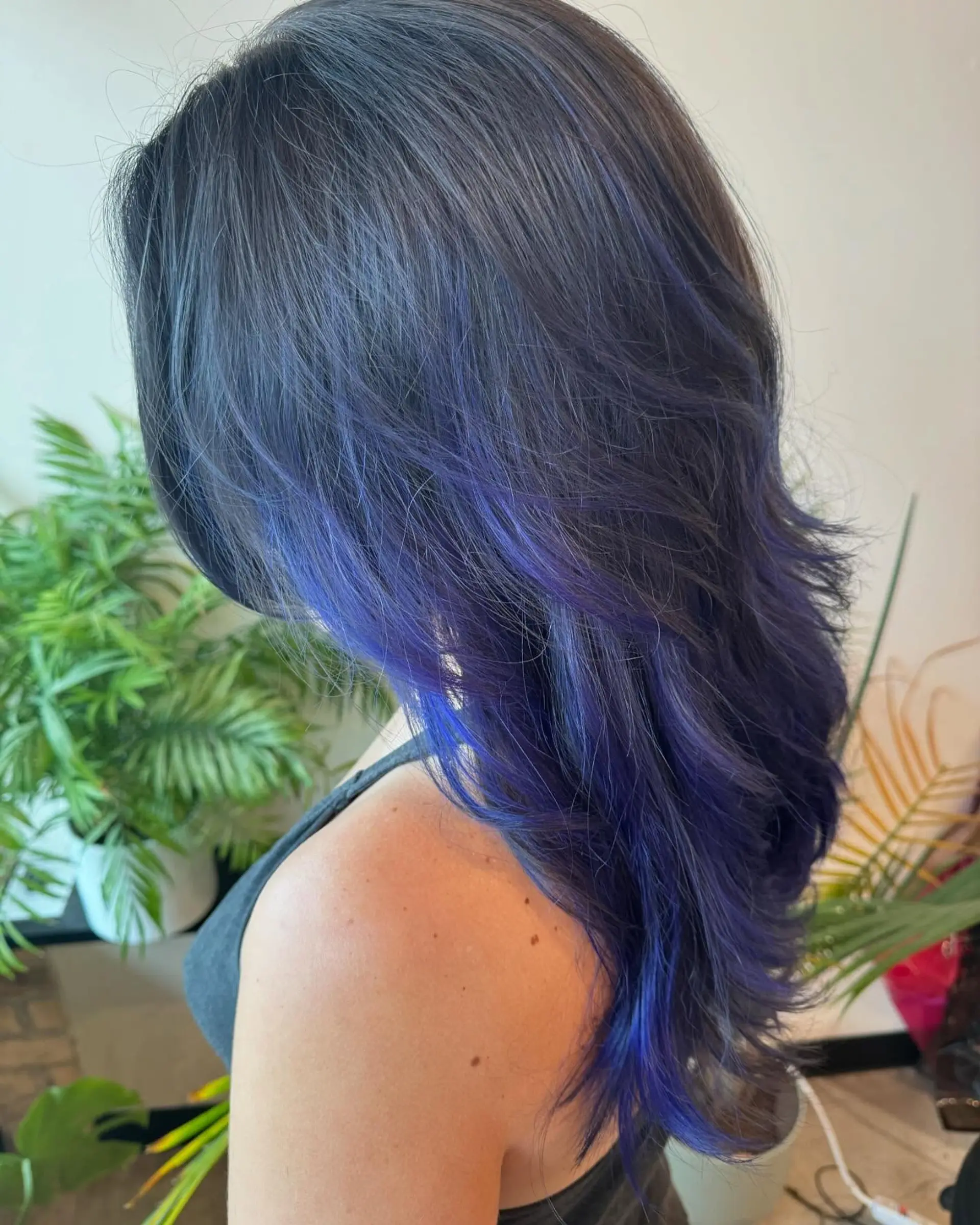Long layered dark hair featuring vivid indigo and royal blue balayage highlights swept through the mid-lengths and ends. 1