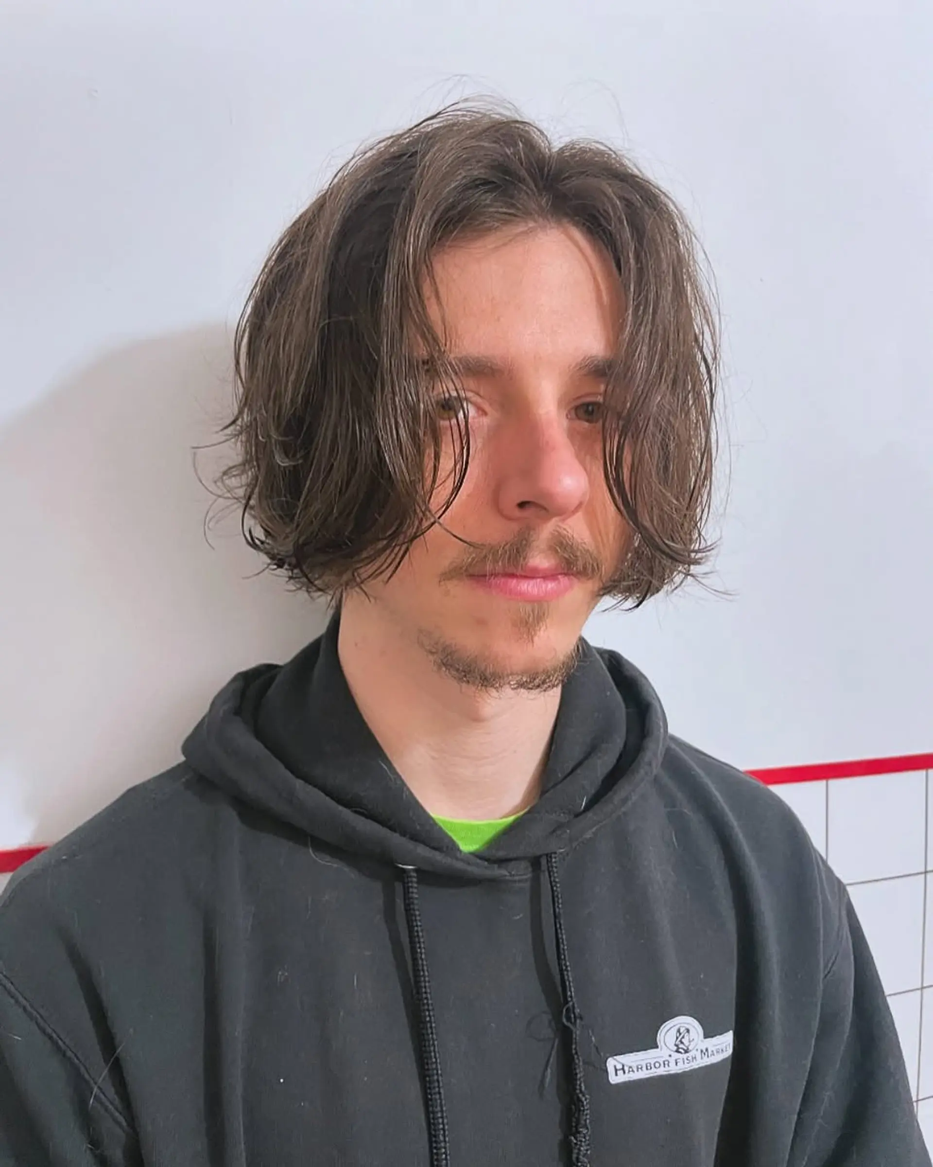 A medium-length cut featuring a distinct middle part with textured, wavy layers that drape around the face in a curtain style. 1
