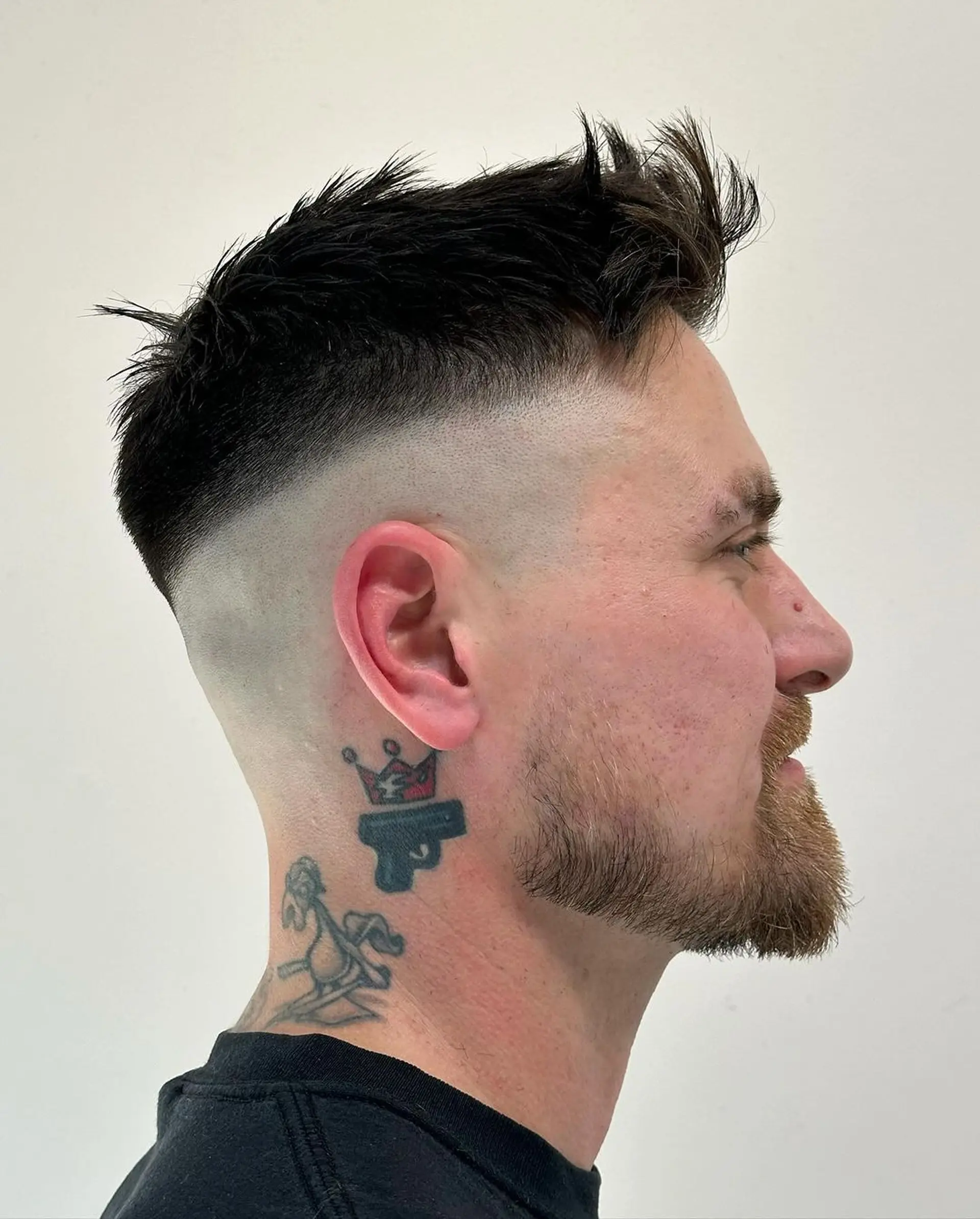 Textured, straight black hair styled into bold spikes with a high fade, offering a punk aesthetic. Short length enhances edge with neat beard alignment. 2