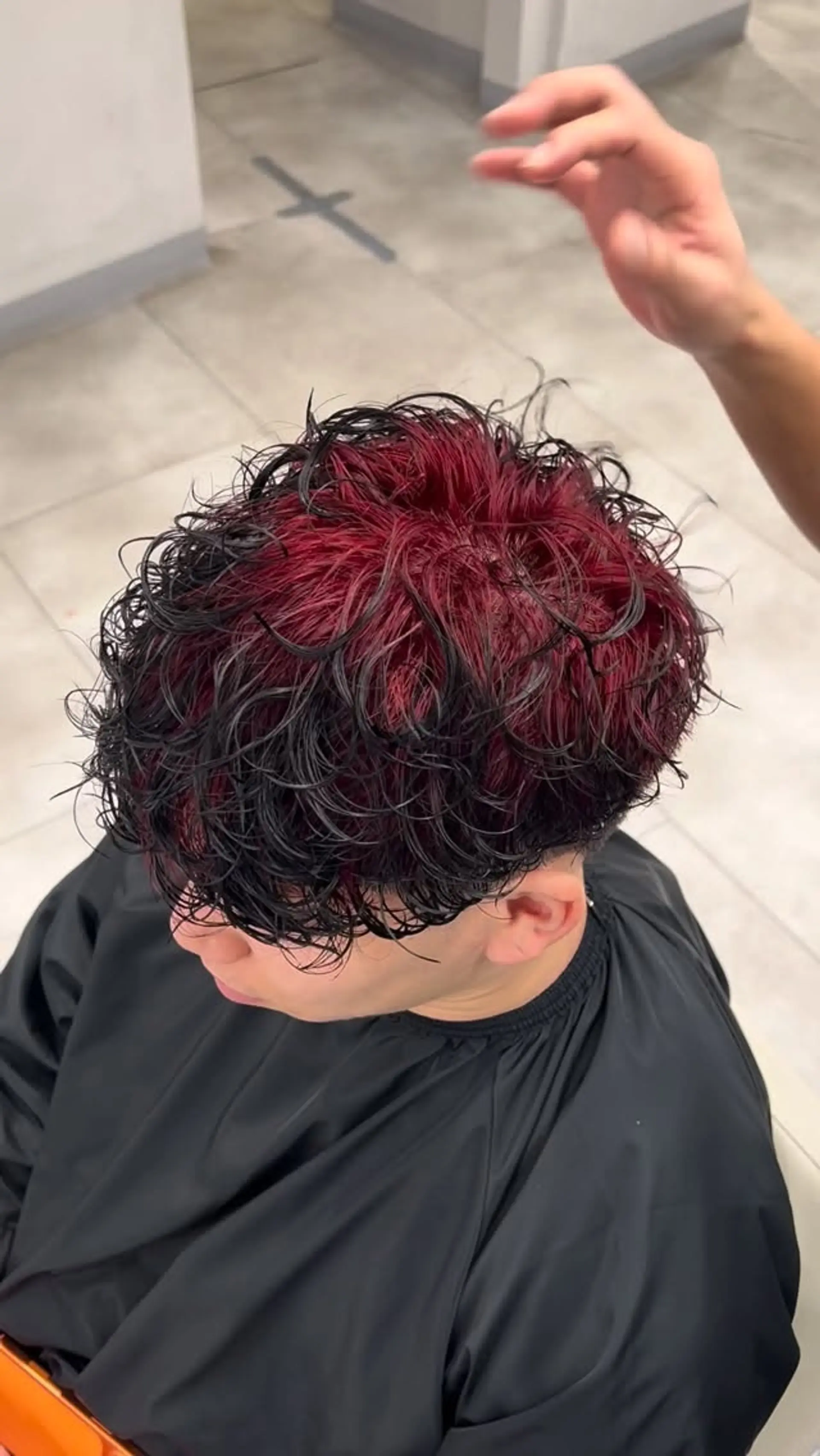 A textured curly crop cut featuring bright red ghost roots contrasting against dark black ends. 1