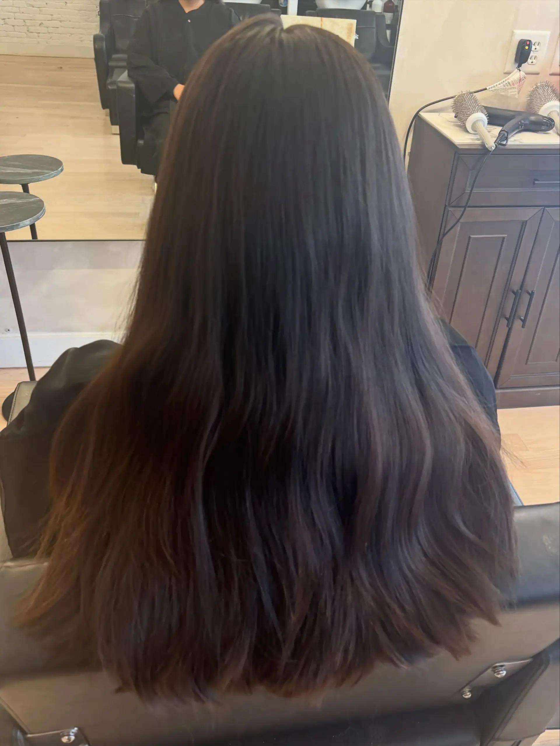 Long, thick dark brunette hair styled straight with a smooth blowout and natural volume. 1