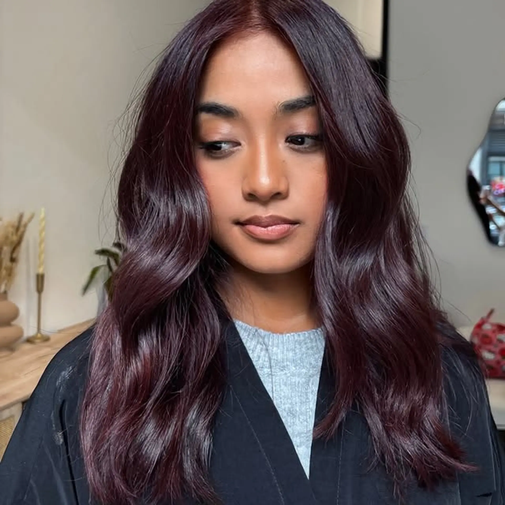 Wavy hairstyle with a rich burgundy and auburn balayage. 1