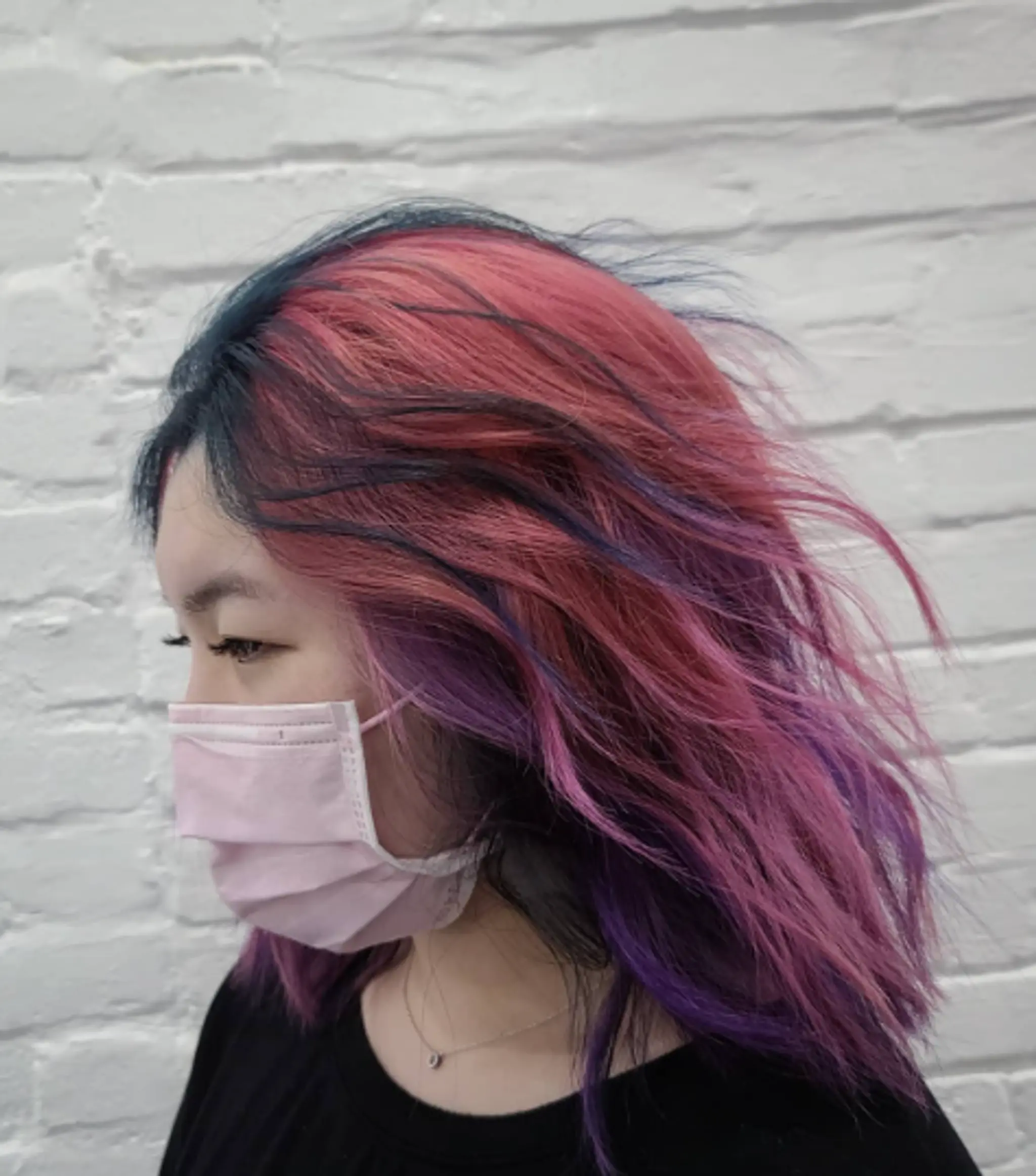 Medium-length wavy hairstyle with vibrant pink, purple, and blue hues; layered and side-parted for added texture and volume.