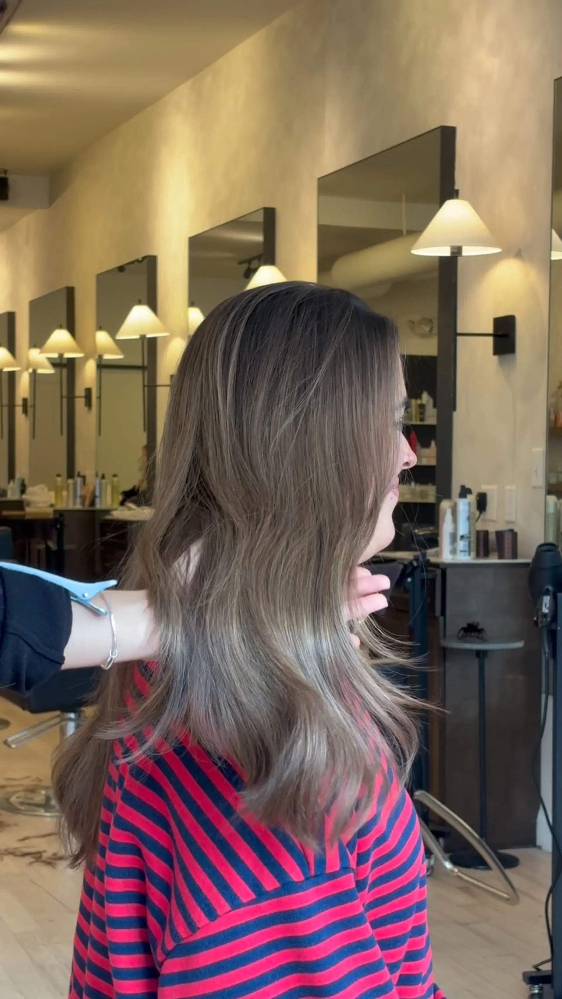A seamless, subtle dimensional brunette color melt styled with a smooth, soft-wave blowout. 1