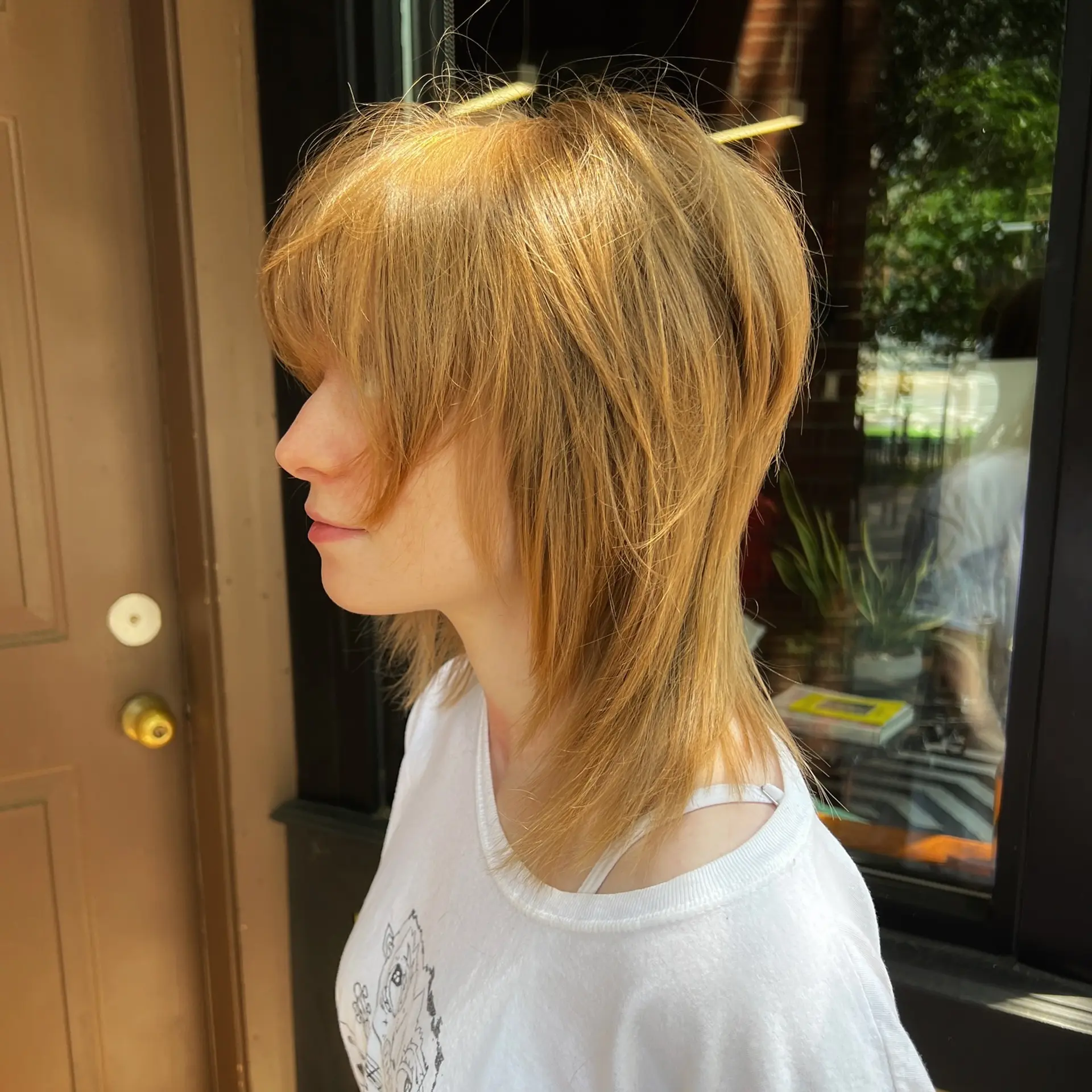A mid-length modern shag haircut featuring heavy bangs, textured face-framing layers, and straight styling. 1