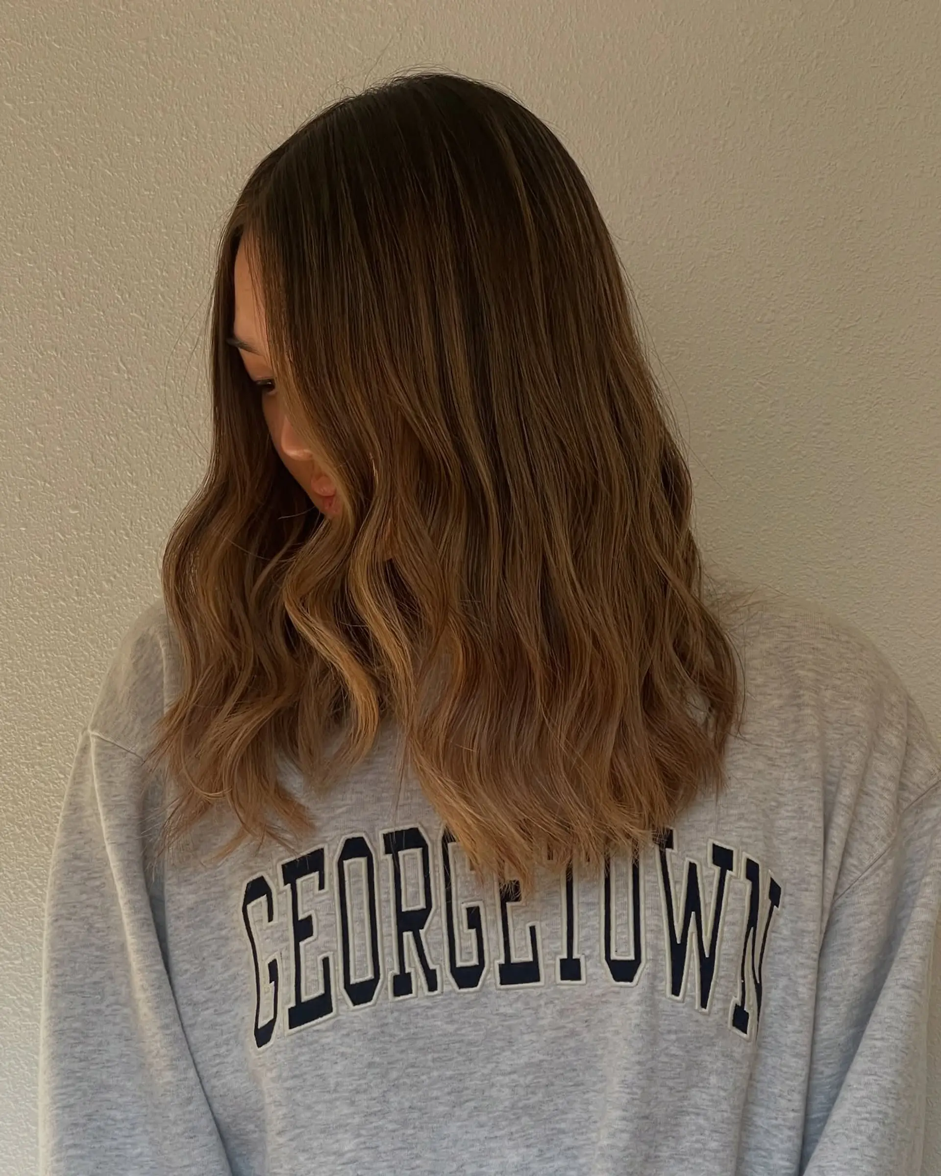 Long dimensional warm brunette hair with blended caramel tones styled into loose waves. 1