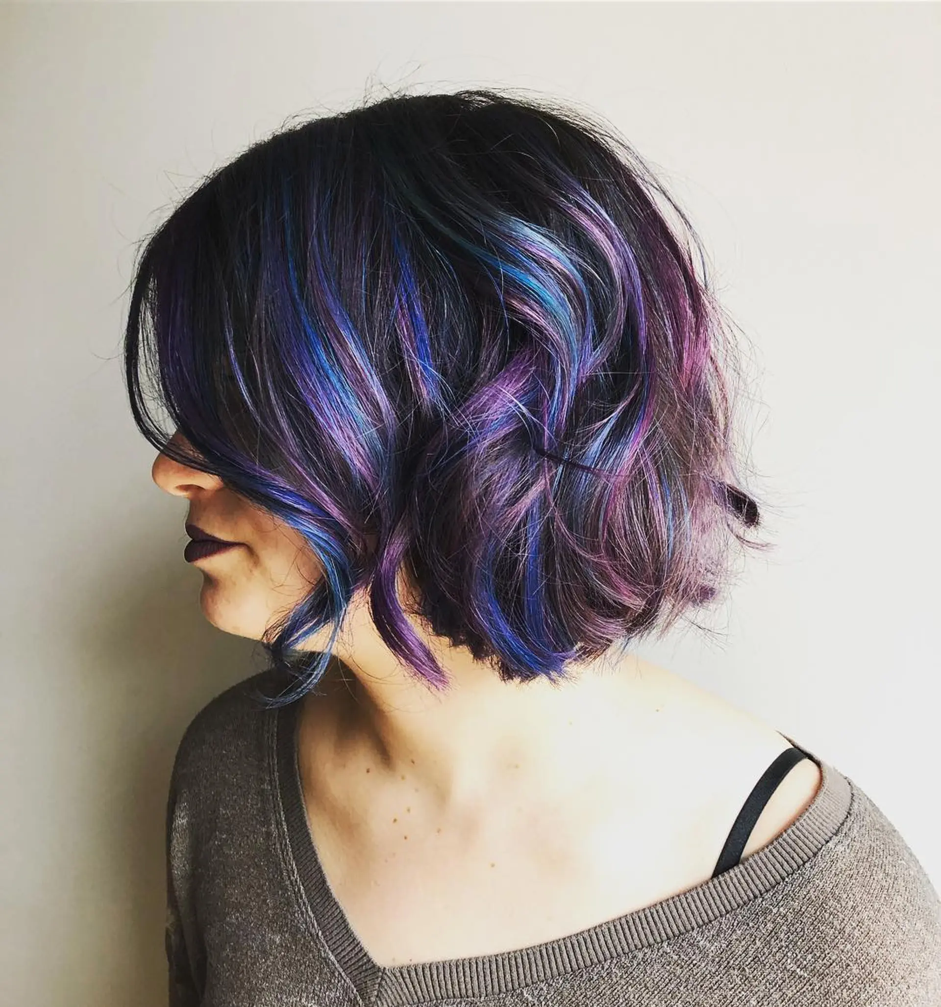 A wavy bob haircut featuring bold, dimensional highlights in shades of blue and purple, creating a vibrant and eye-catching look. 1
