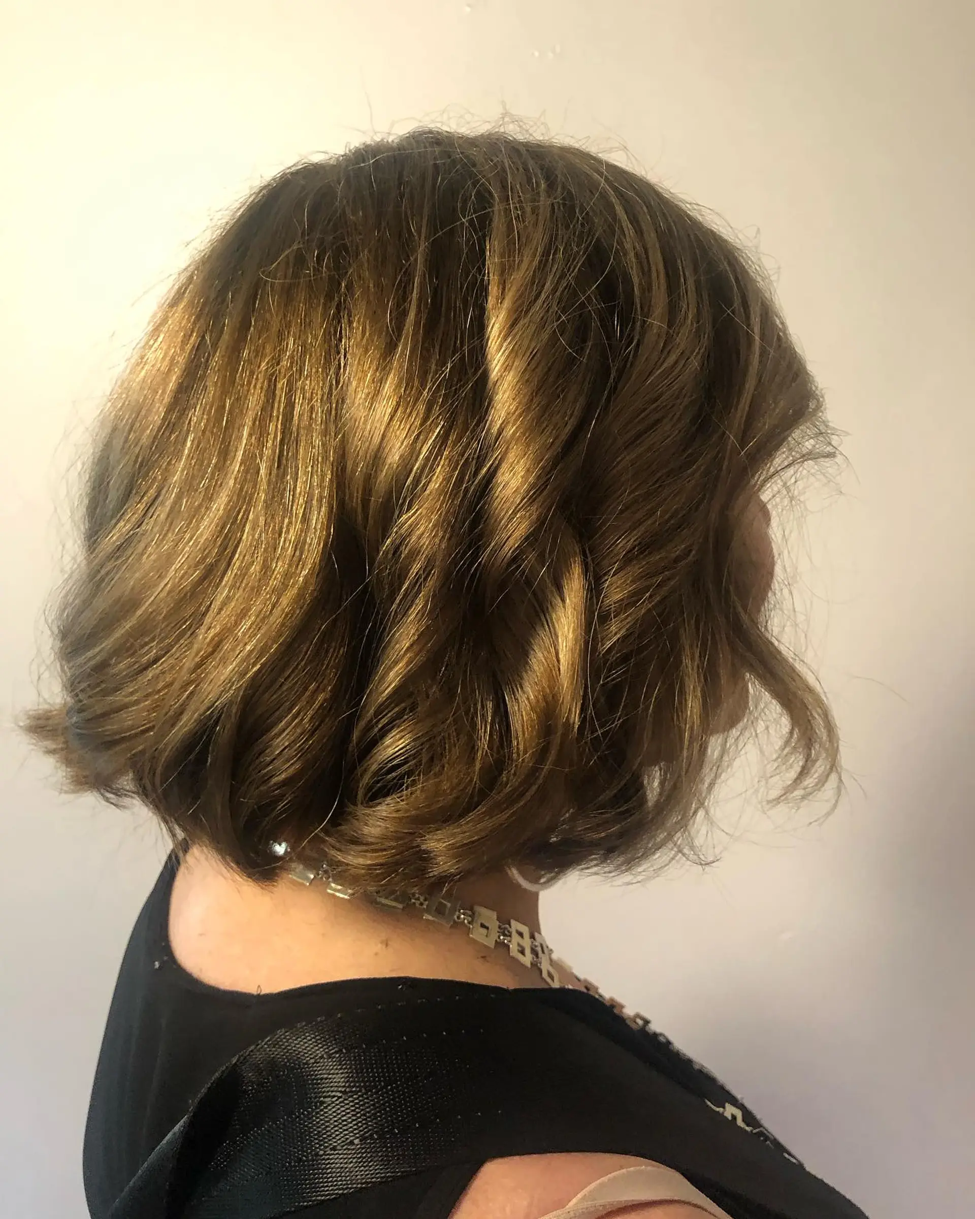 A textured chin-length bob styled with soft, loose waves and finished in a glossy golden brown glaze. 1