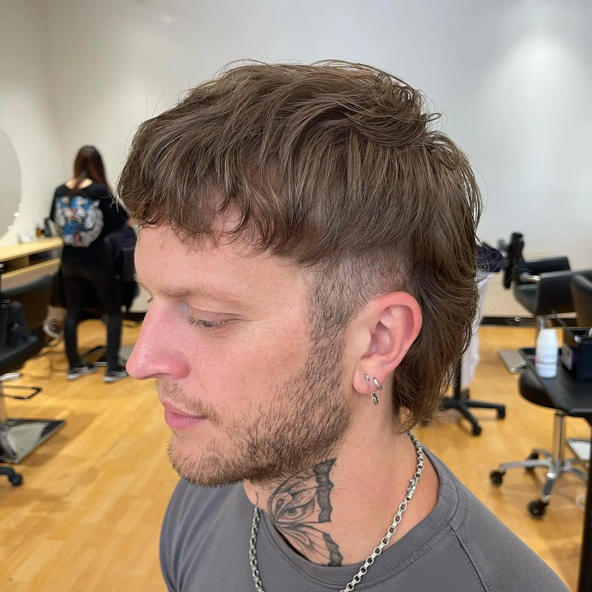 A modern textured mullet featuring short cropped fringe, faded temples, and longer layered length tapering down the back of the neck. 1