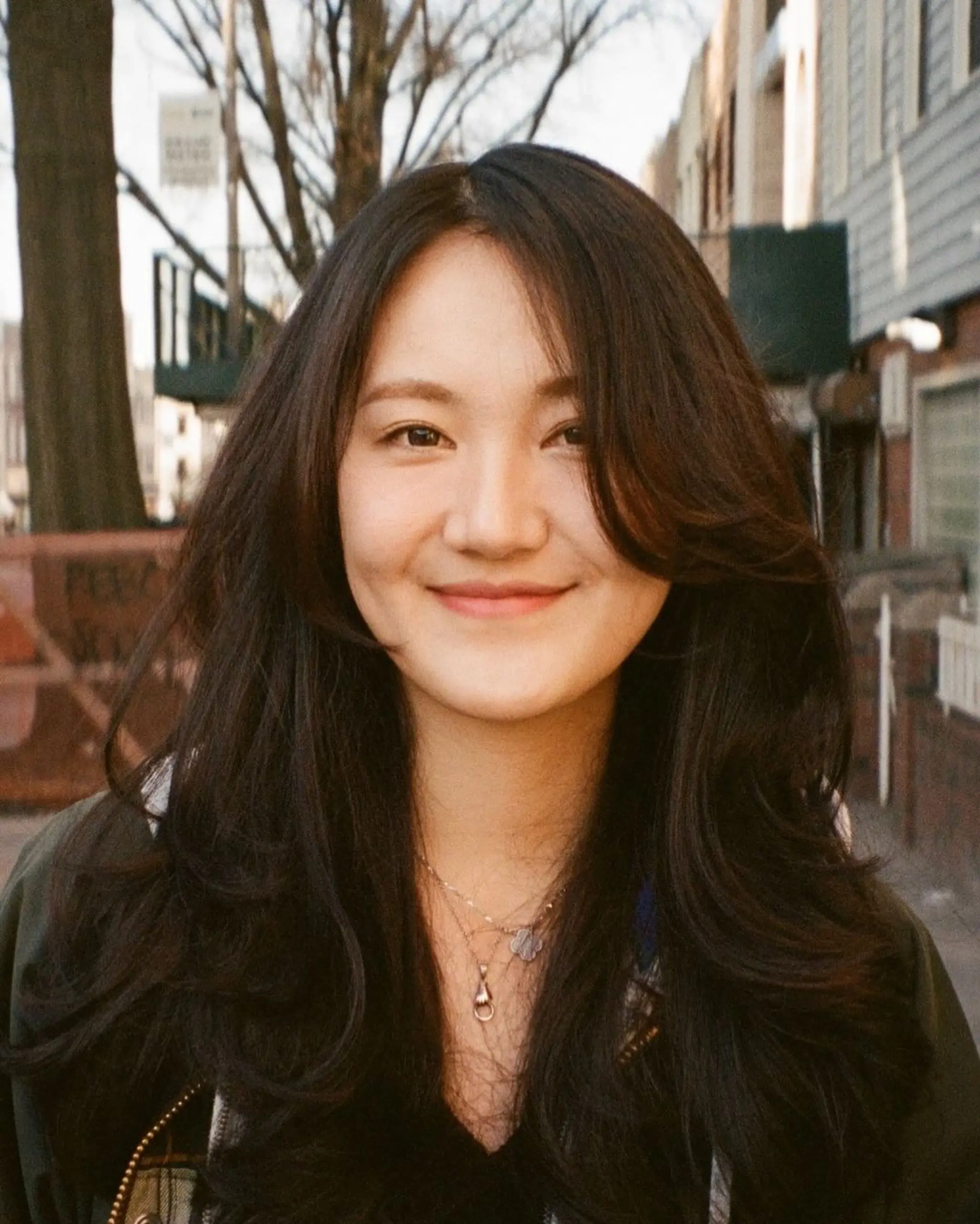 Long, wavy hair with dark brown color, featuring soft layers and side-swept bangs, offering natural shine and voluminous body.