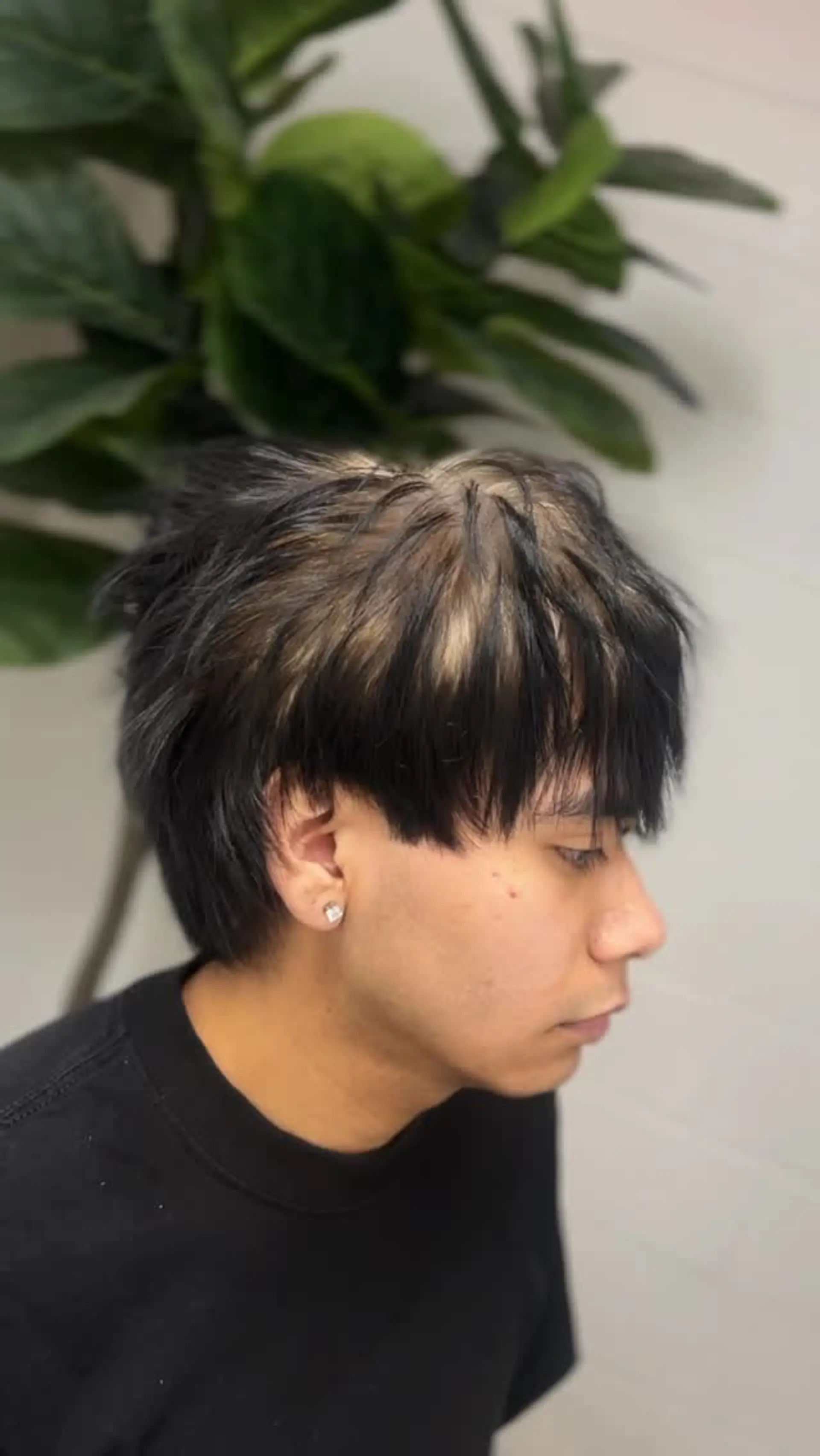 A textured short haircut featuring light blonde ghost roots peeking through edgy black crown layers and fringe. 1