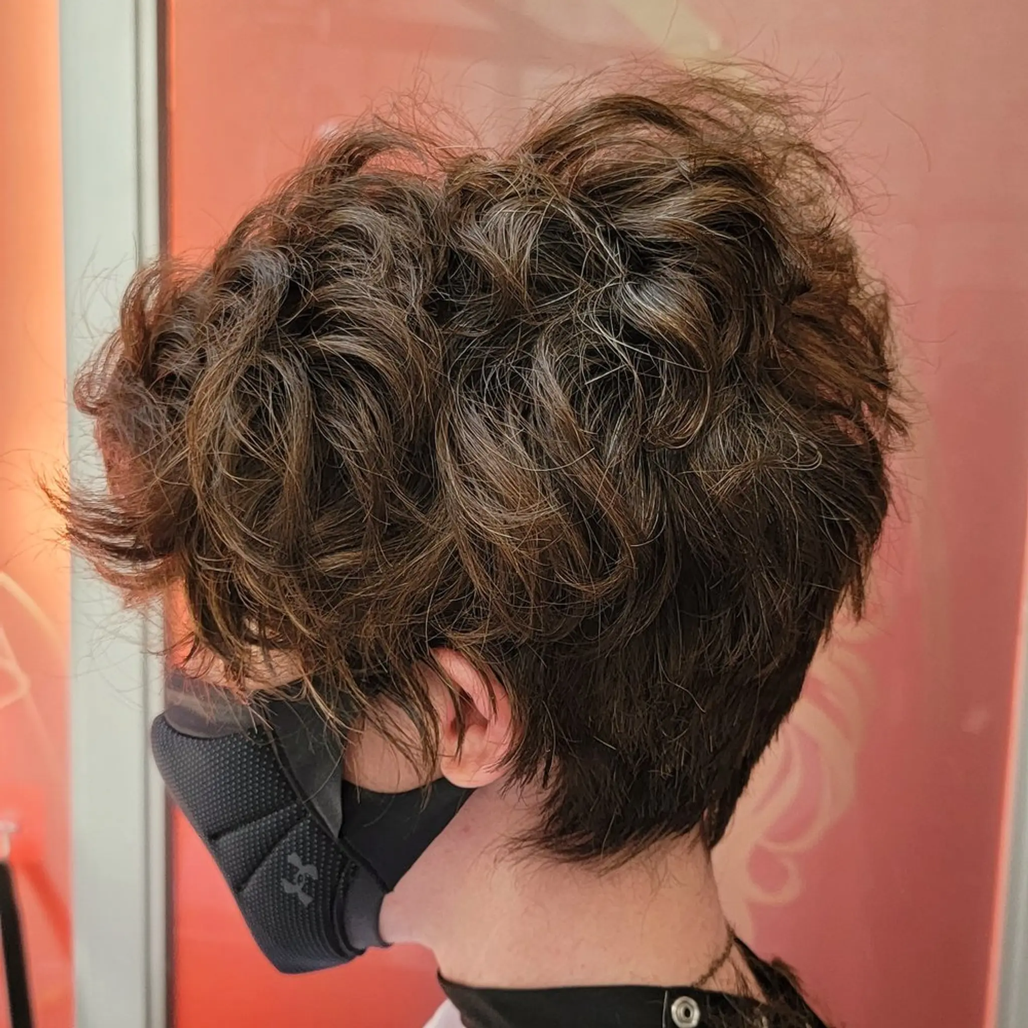Short, naturally curly hair with a voluminous, tousled texture, slightly layered for added bounce and movement.