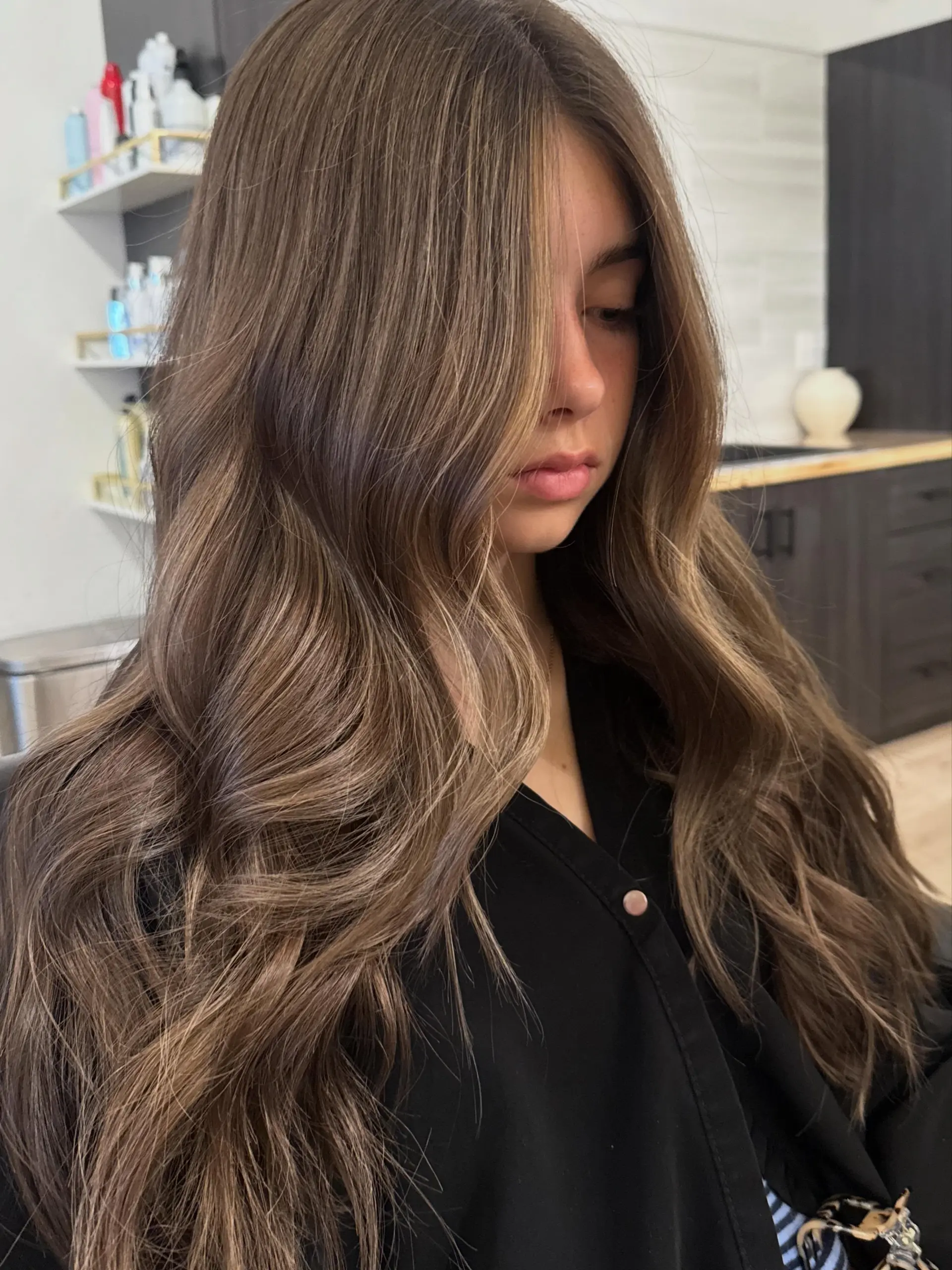 Long dimensional ash-brunette hair styled in loose, voluminous waves. 1