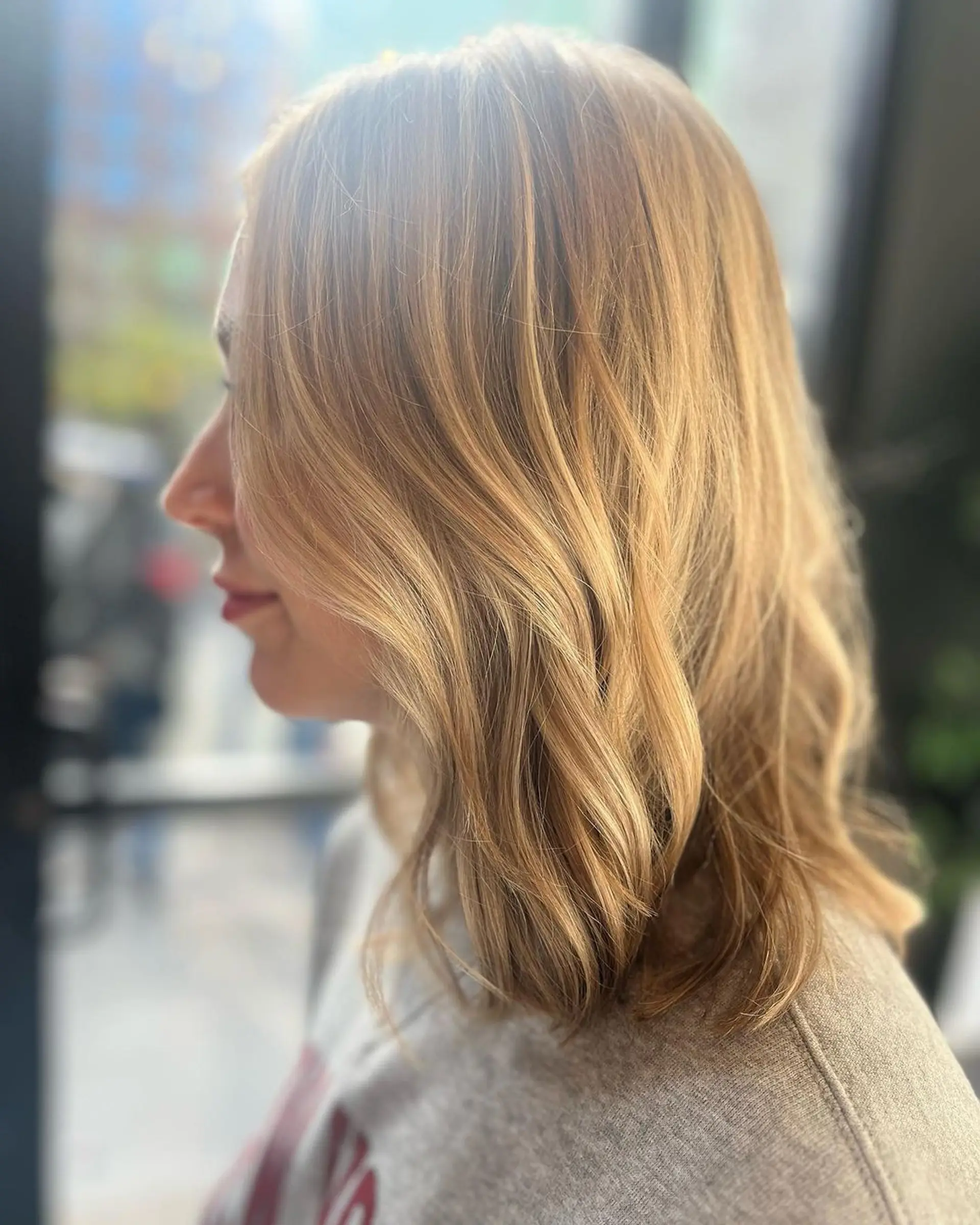 Medium-length wavy blonde hair with natural waves and soft layers, featuring a side part and sun-kissed highlights. 1