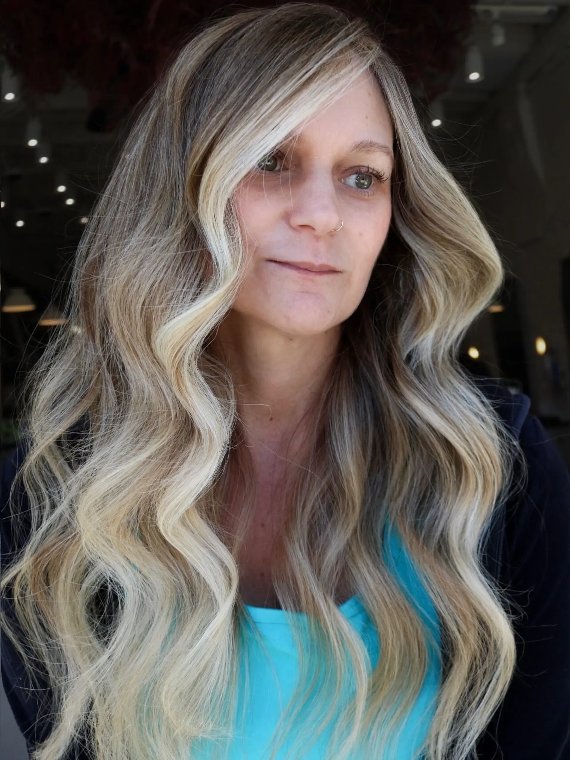 Long lived-in blonde hair styled with soft, glamorous waves and a bright face-framing money piece. 1