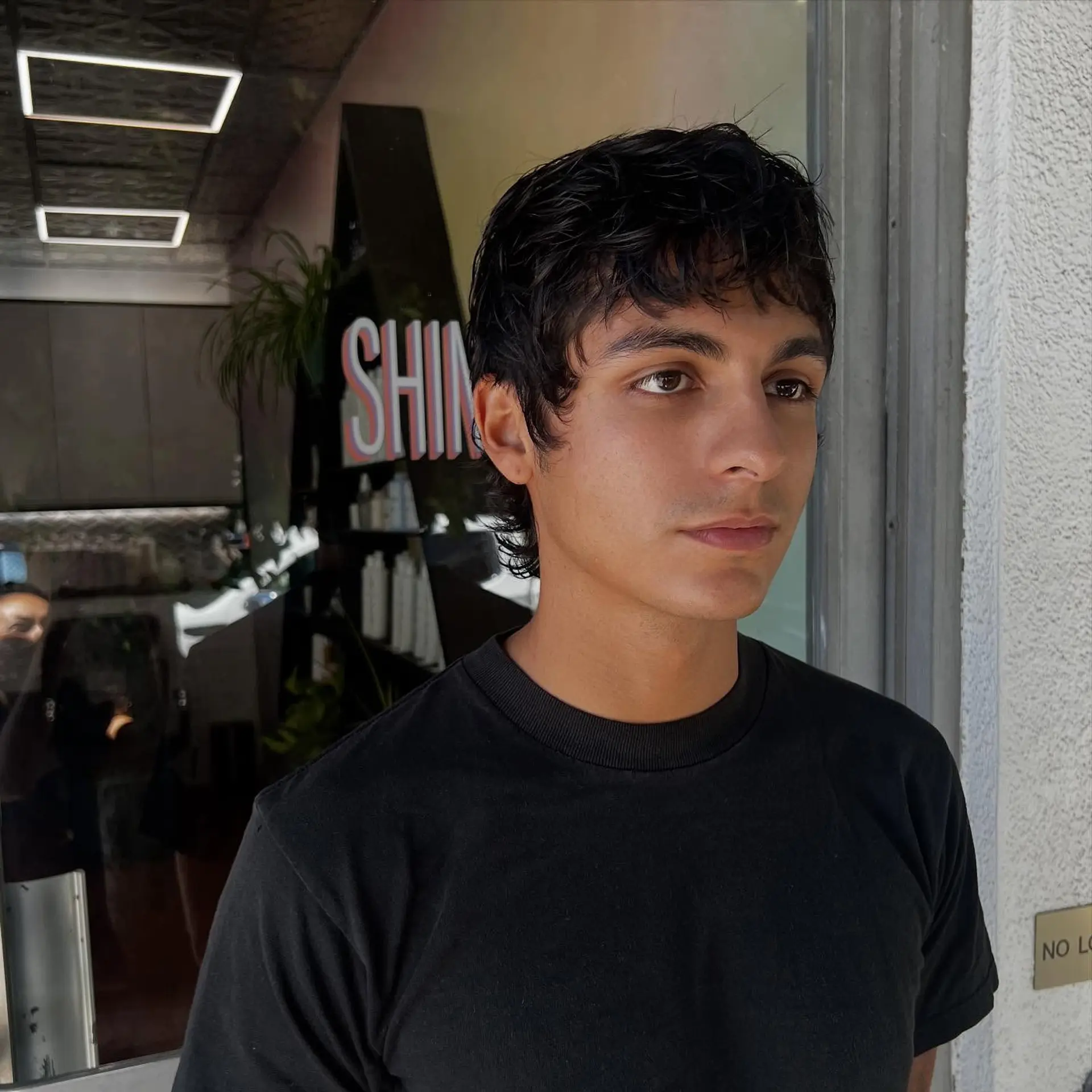 A textured modern mullet haircut with piecey bangs, short tapered sides, and soft length at the nape. 1