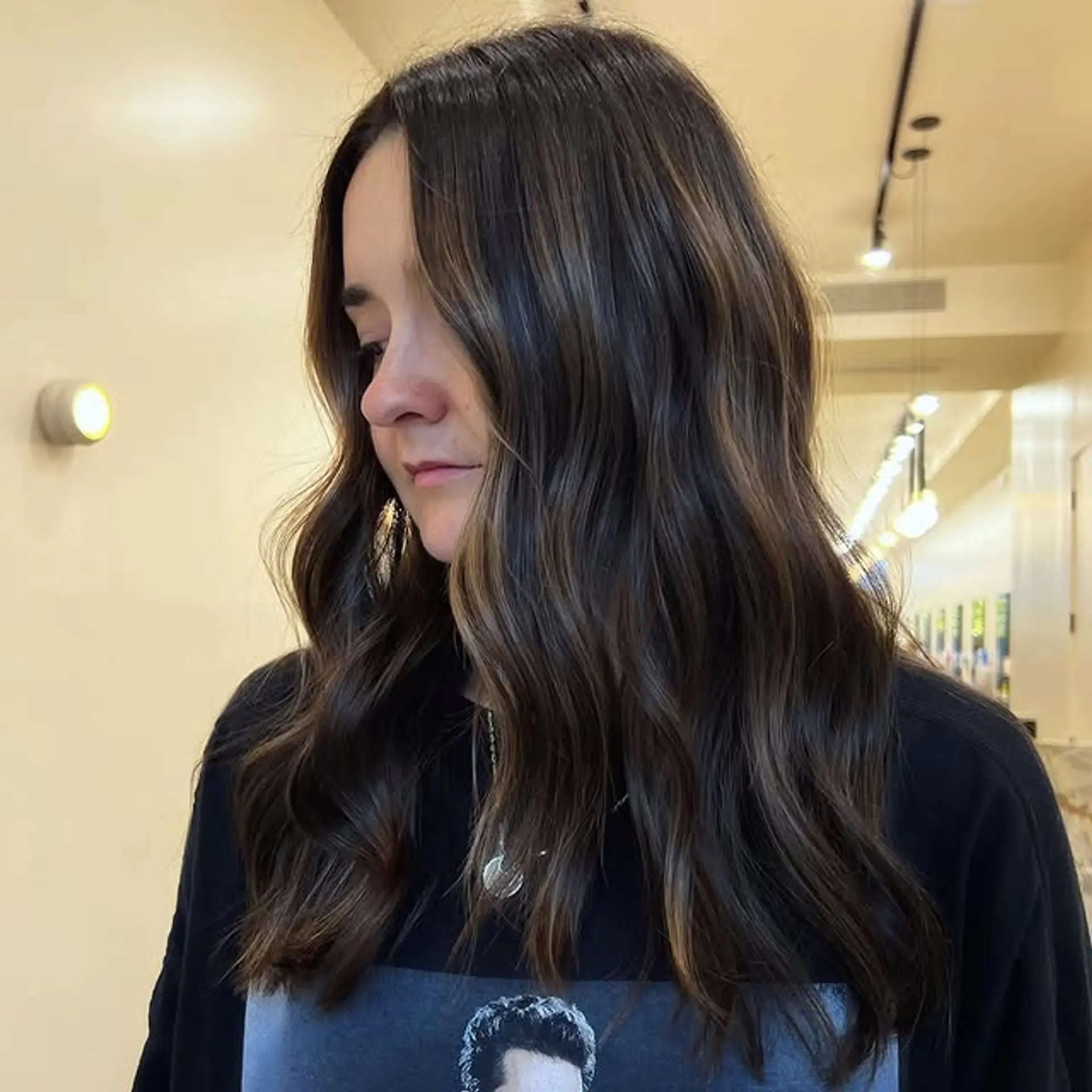 Wavy, medium-length hairstyle with bronzed brunette balayage highlights. 1