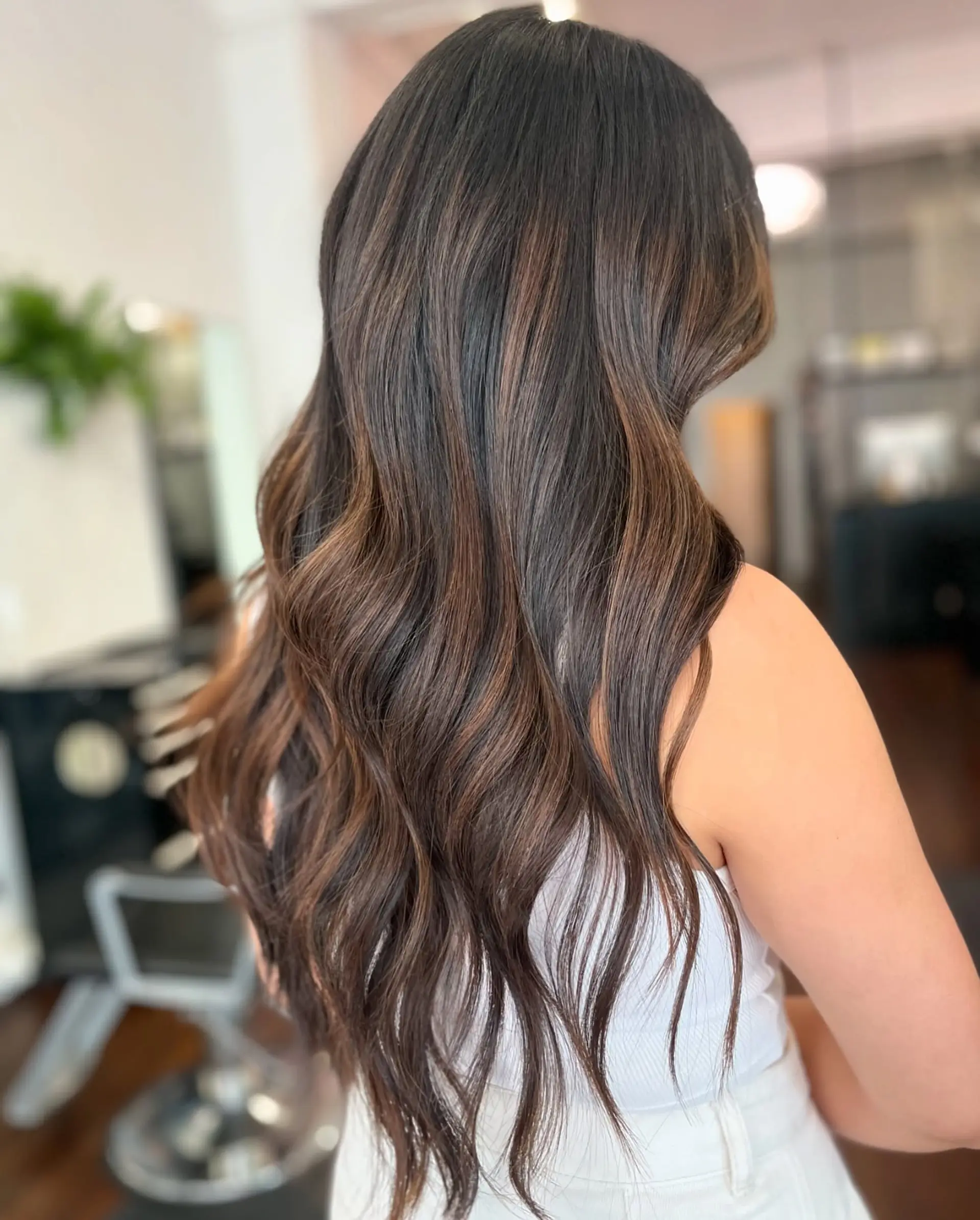 Long chocolate brown hair styled with soft, loose waves and subtle dimensional balayage highlights. 1