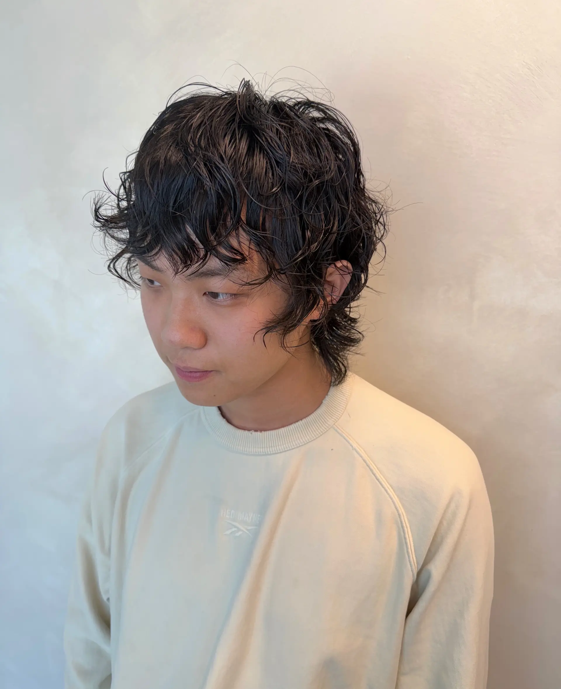 A medium-short textured perm with a wet-look finish styled into a modern layered mullet with wavy fringe. 1