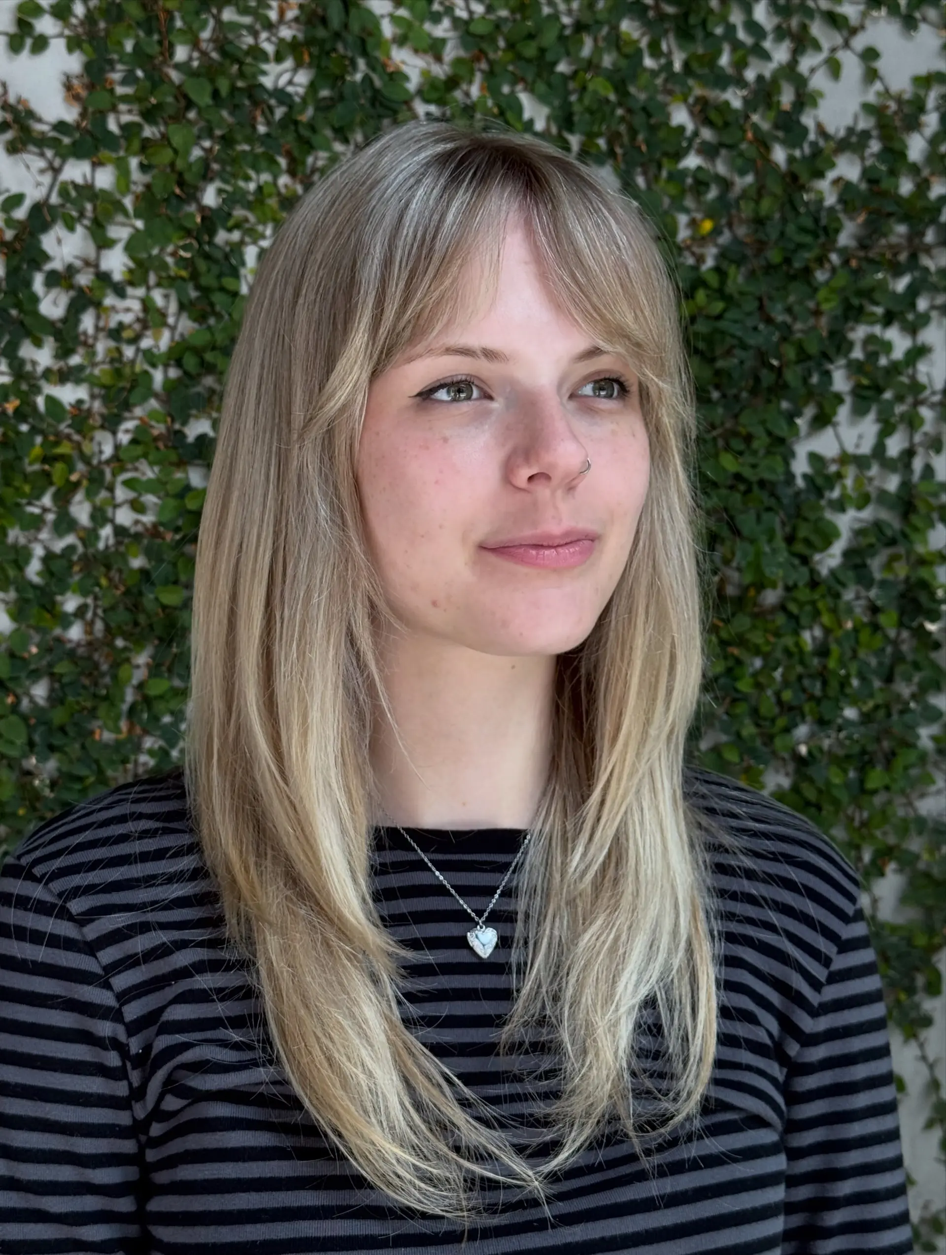 Straight ash blonde long hair featuring soft face-framing layers and wispy curtain bangs. 1