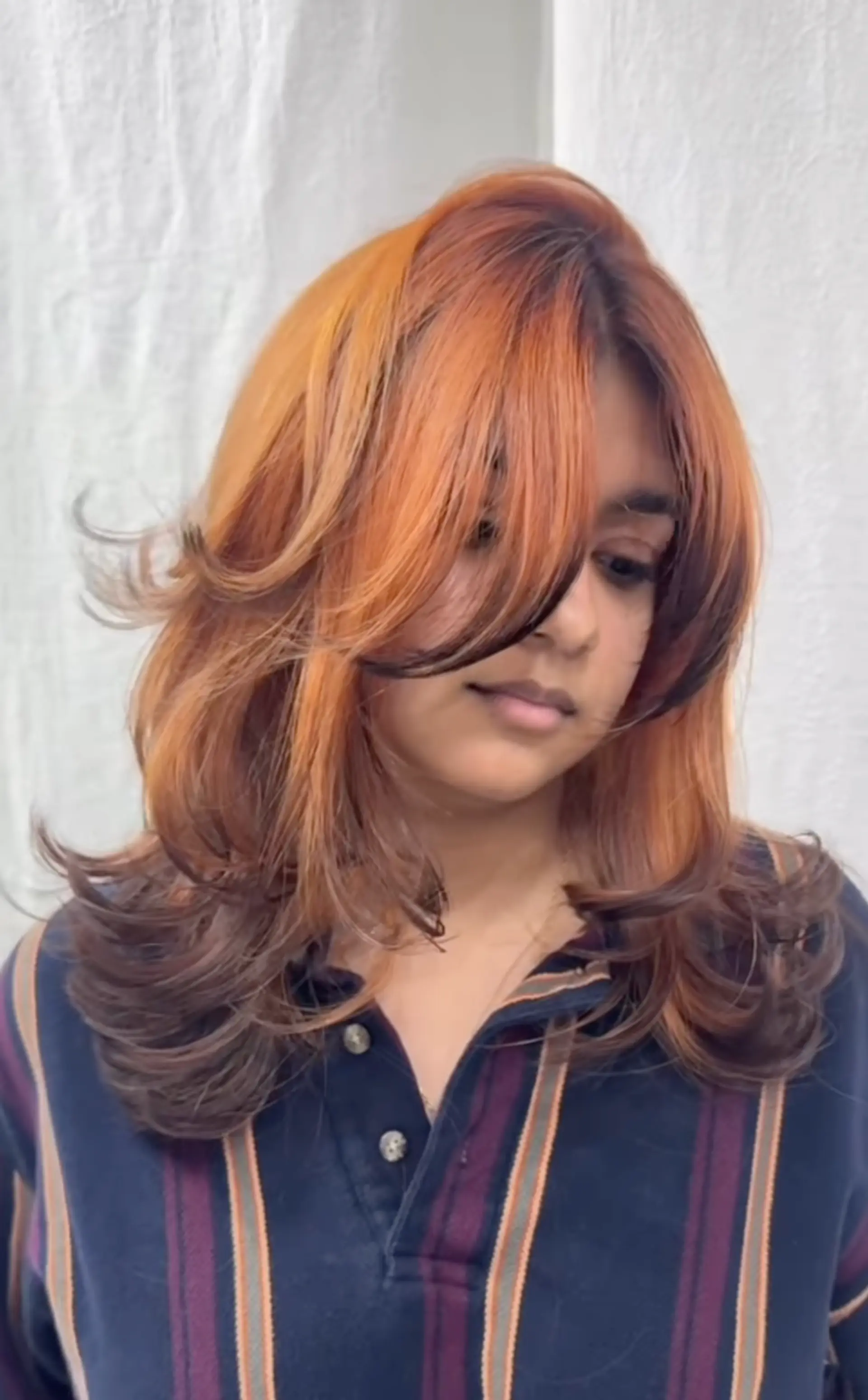 Medium-length, wavy layers with auburn, honey blonde, and chestnut colors. Features fringed bangs and feathered ends. 1