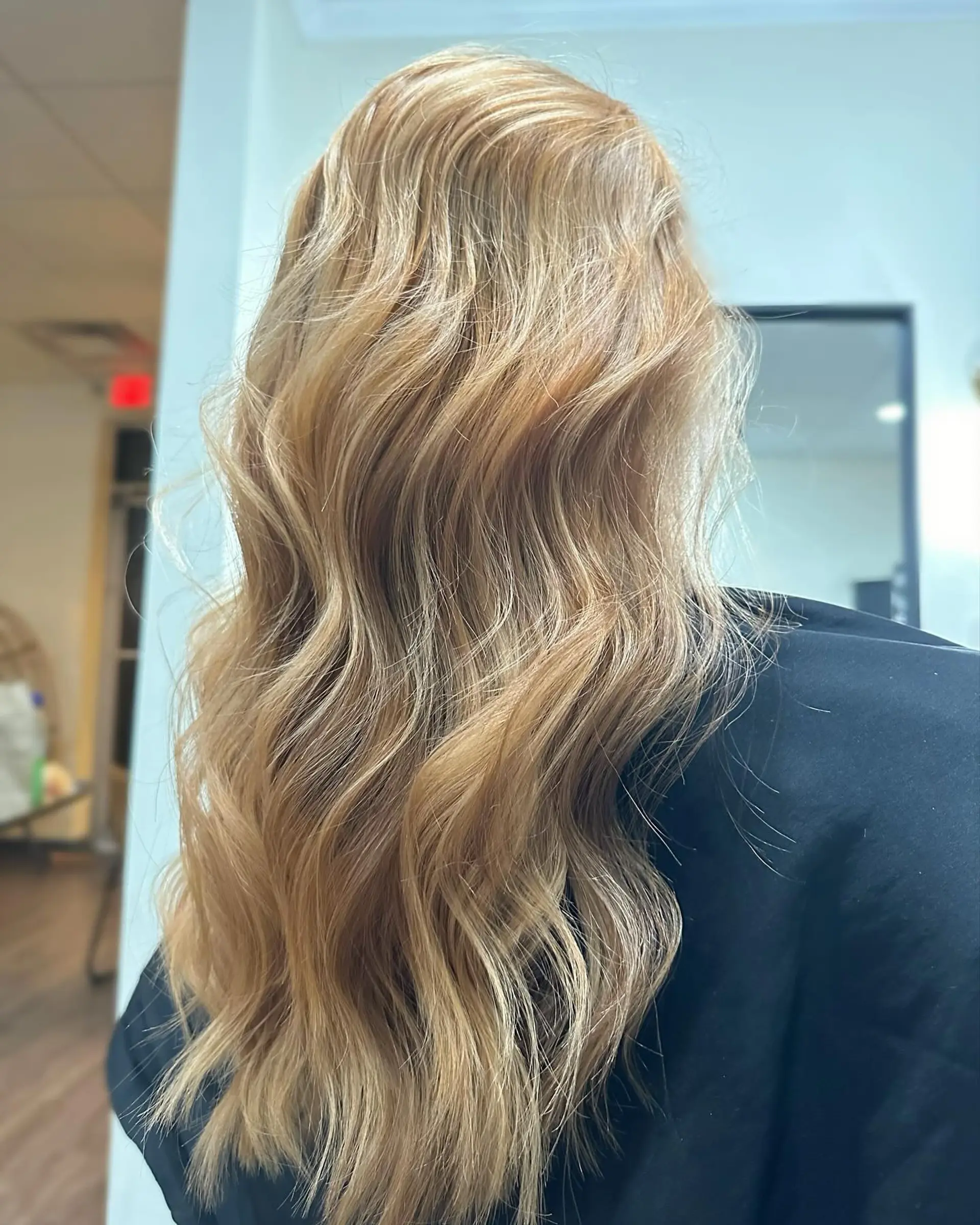 Long warm golden blonde hair styled into soft, loose waves. 1
