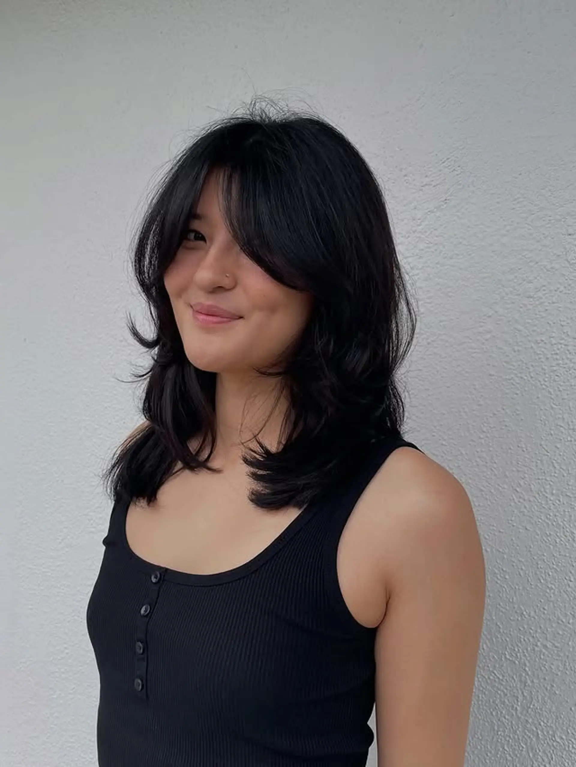 A medium-length wavy hairstyle with curtain bangs and layered face-framing. 1