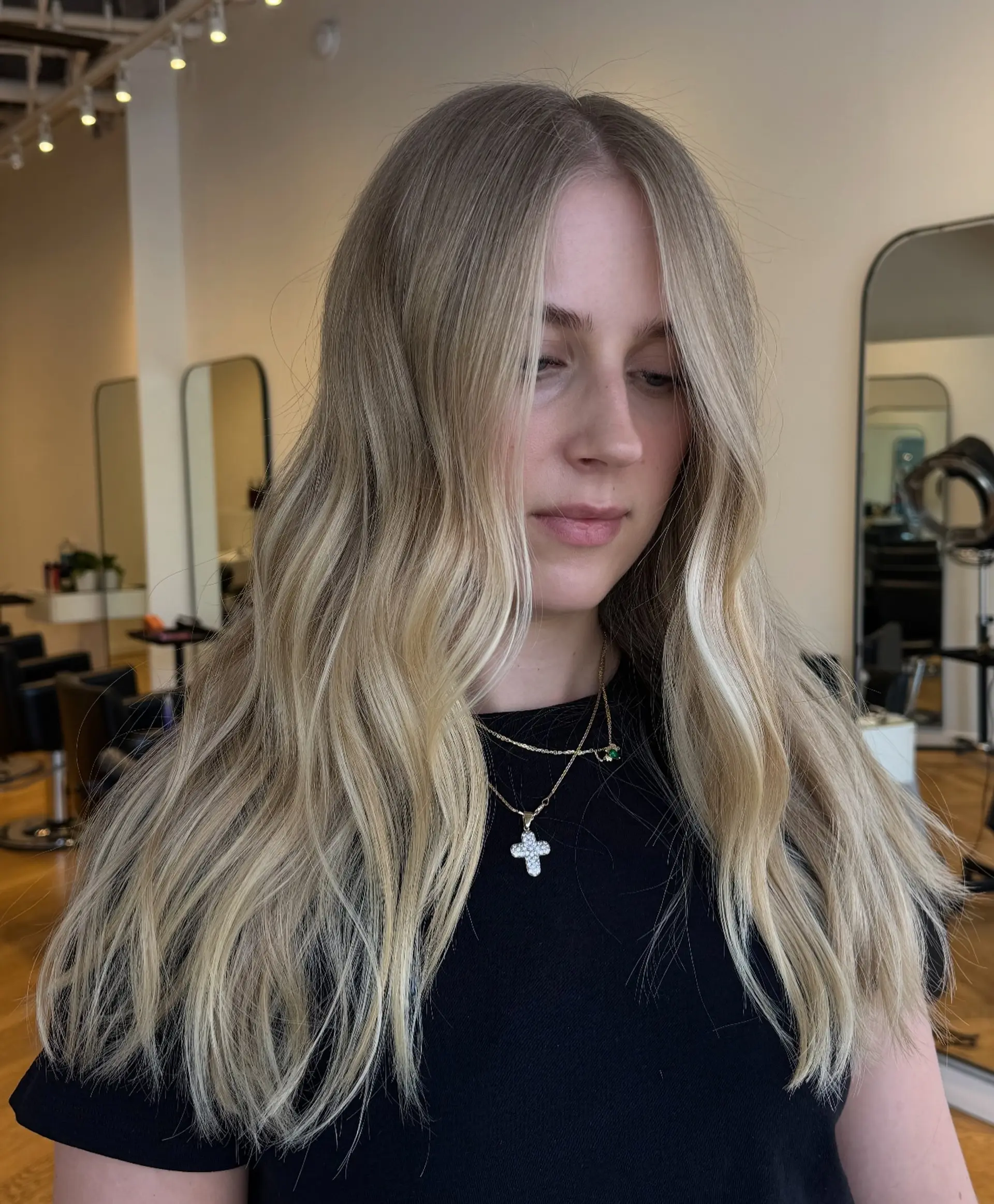 Long center-parted hair styled in loose waves with bright blonde highlights and face-framing accents. 1
