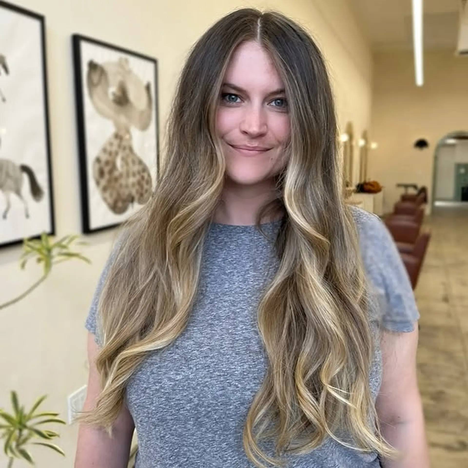 Long layered hair with a balayage creating a brown to blonde gradient, styled with soft waves. 1