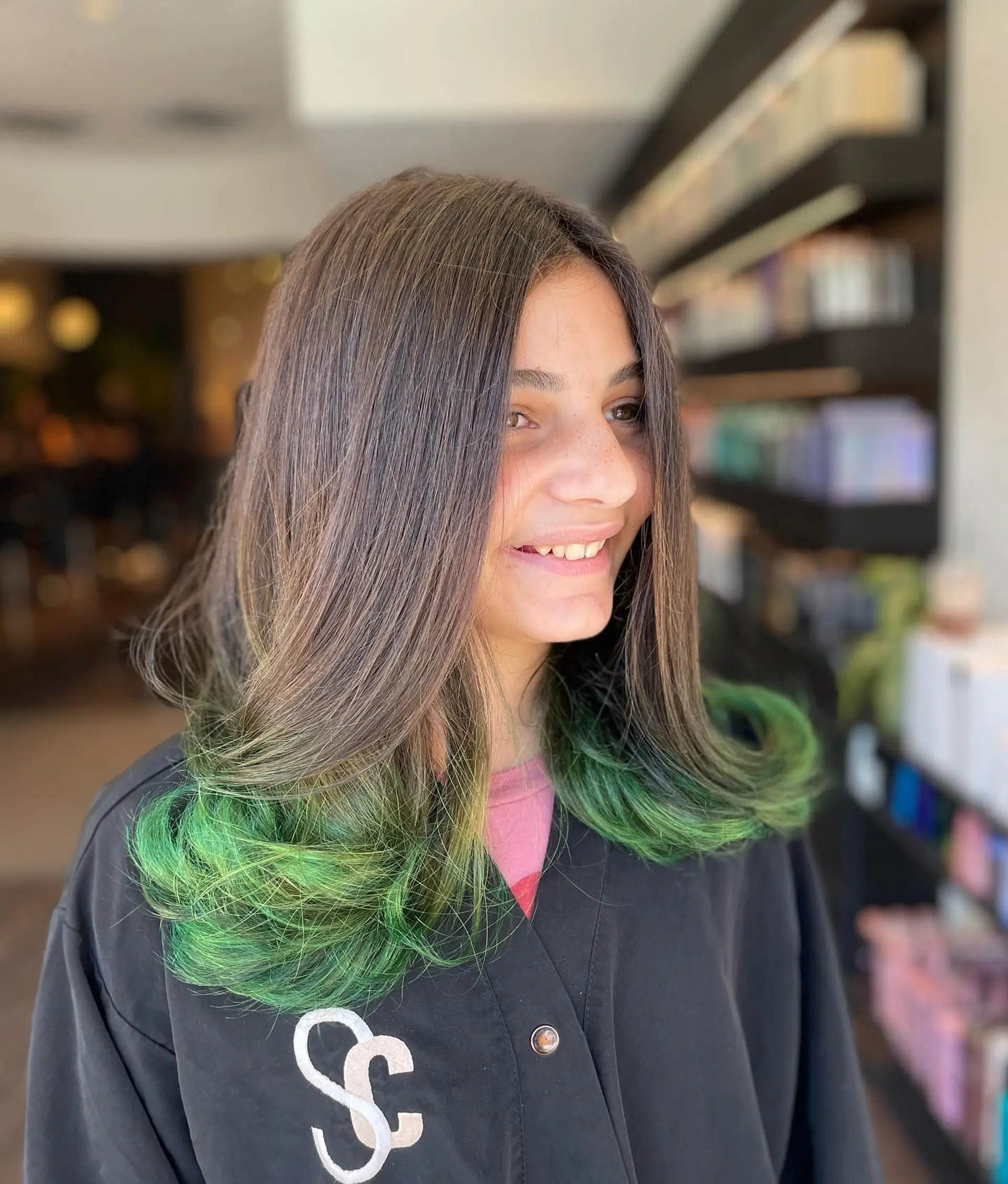 Medium-length dark brown hair featuring vivid green dip-dyed ends styled into soft, flipped-up curls. 1