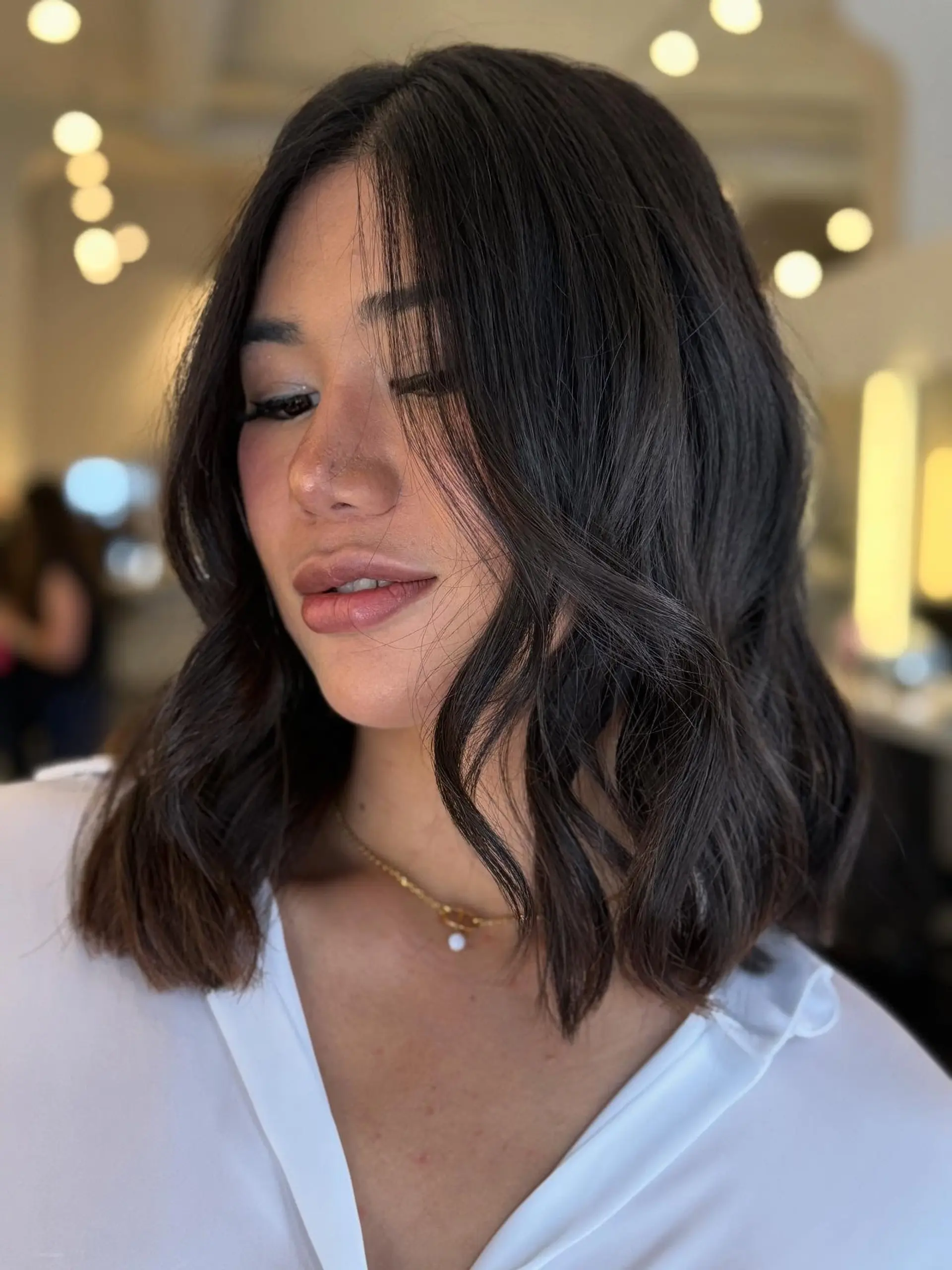 A textured shoulder-length dark brown lob styled with relaxed, effortless waves. 1