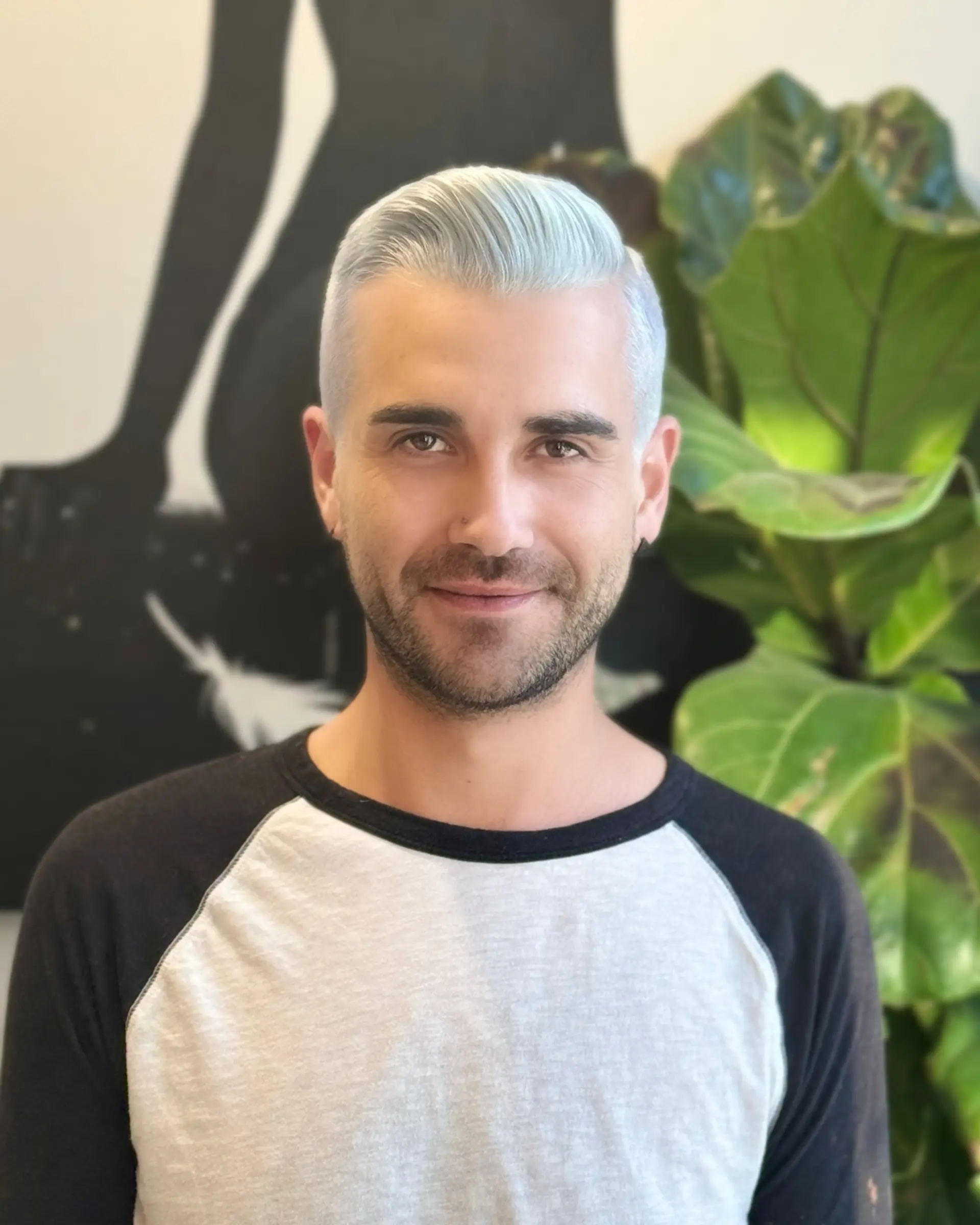 A sleek, short style with closely clipped sides and longer top hair brushed back in a cool icy platinum tone. 1