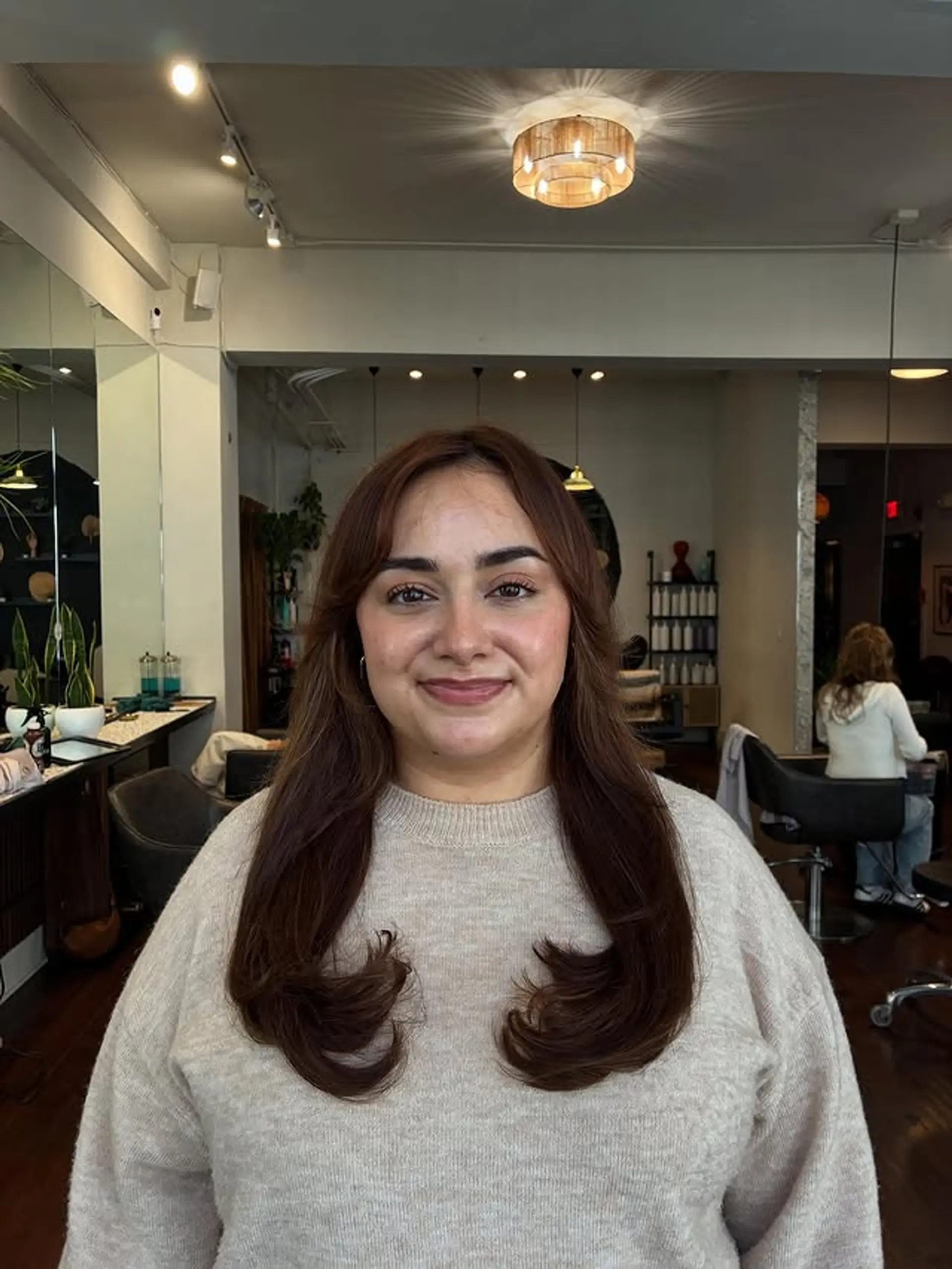 Long layered hair with face-framing curtain bangs and soft waves. 1