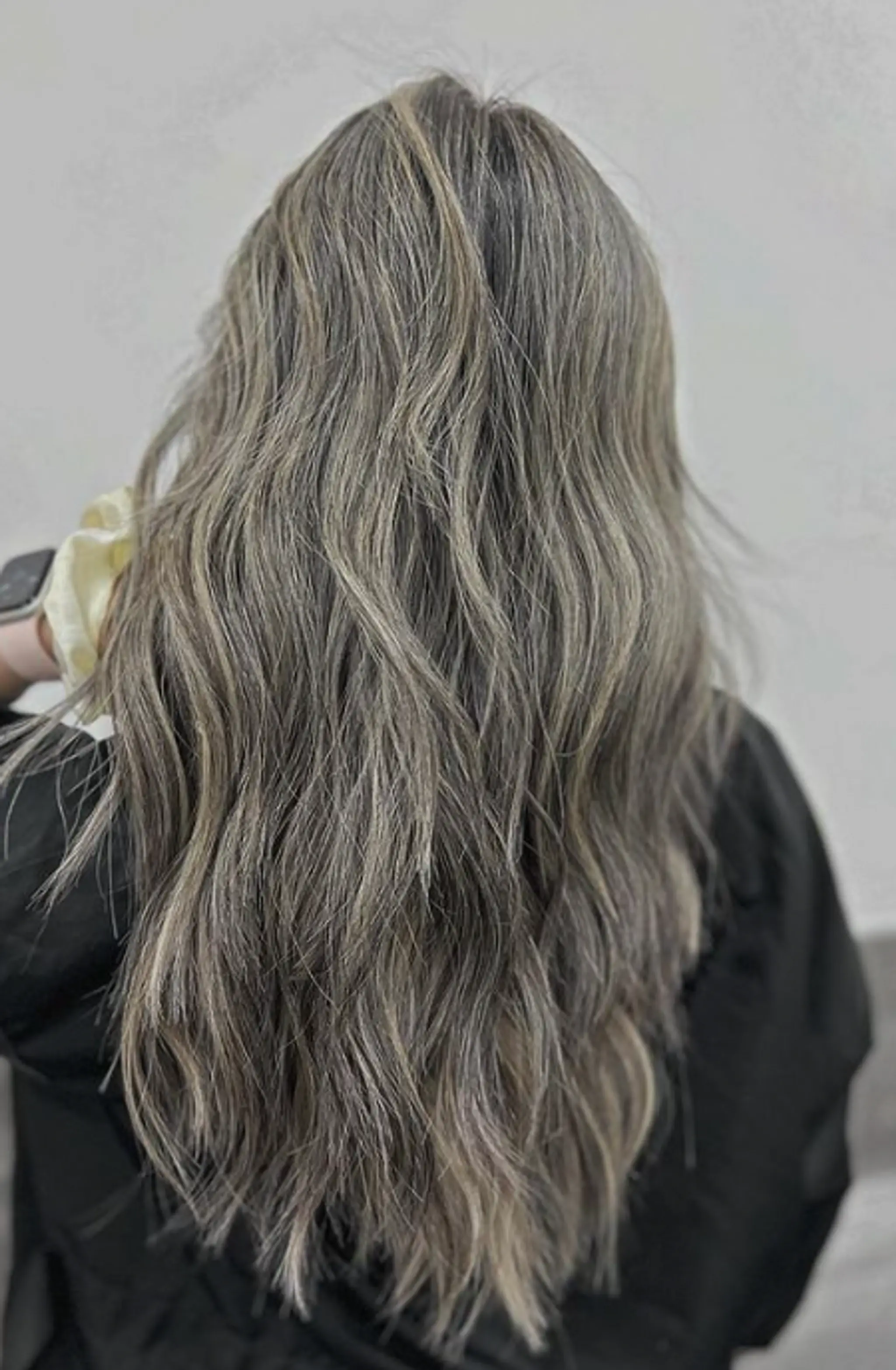 Long, wavy hair with a blend of platinum blonde and ash tones, featuring well-blended highlights and natural volume.
