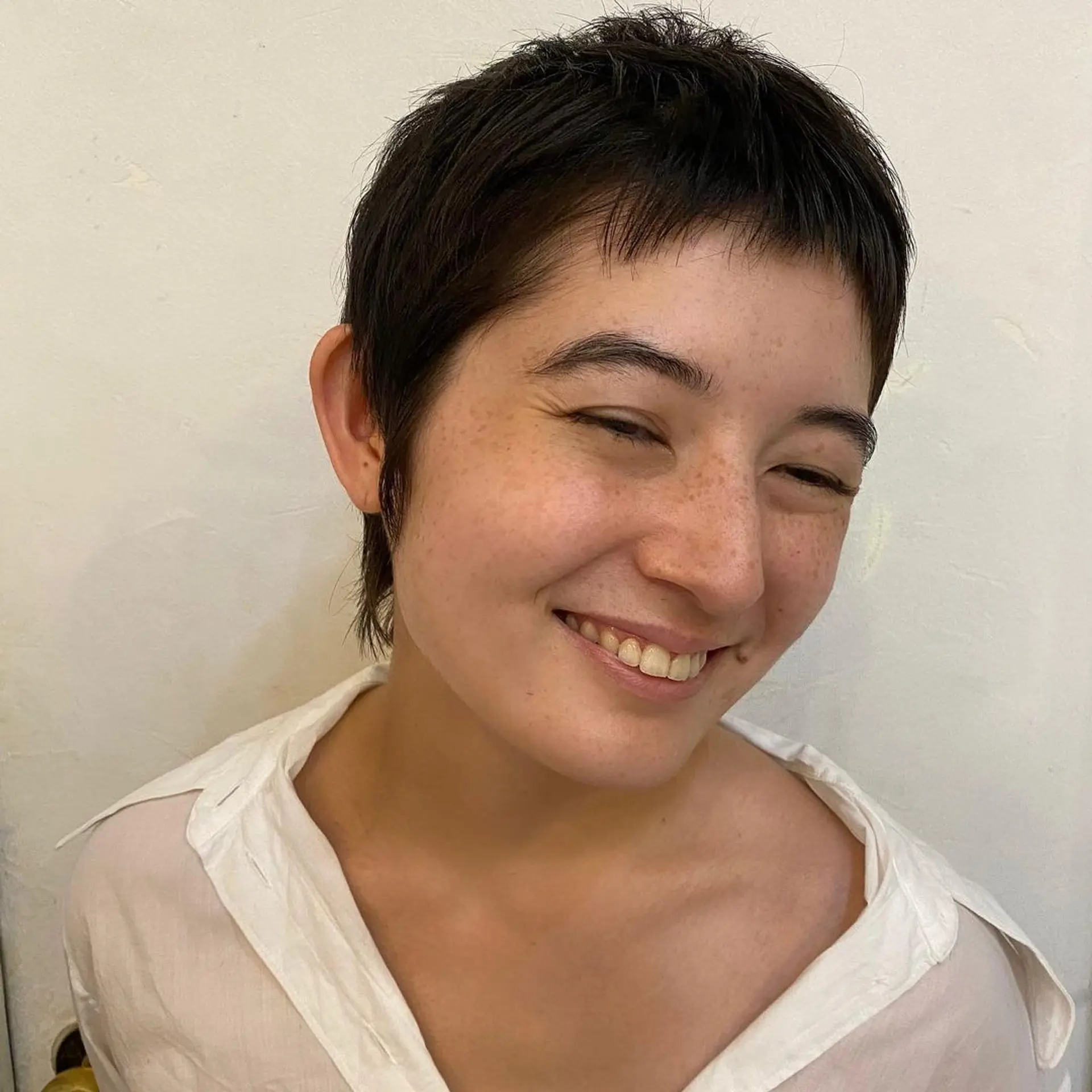A sleek, textured pixie cut with uniformly short, dark brown hair. Features include slightly longer pieces at the crown for volume, and straight-cut bangs with a bit of unevenness for a modern, edgy look. 3