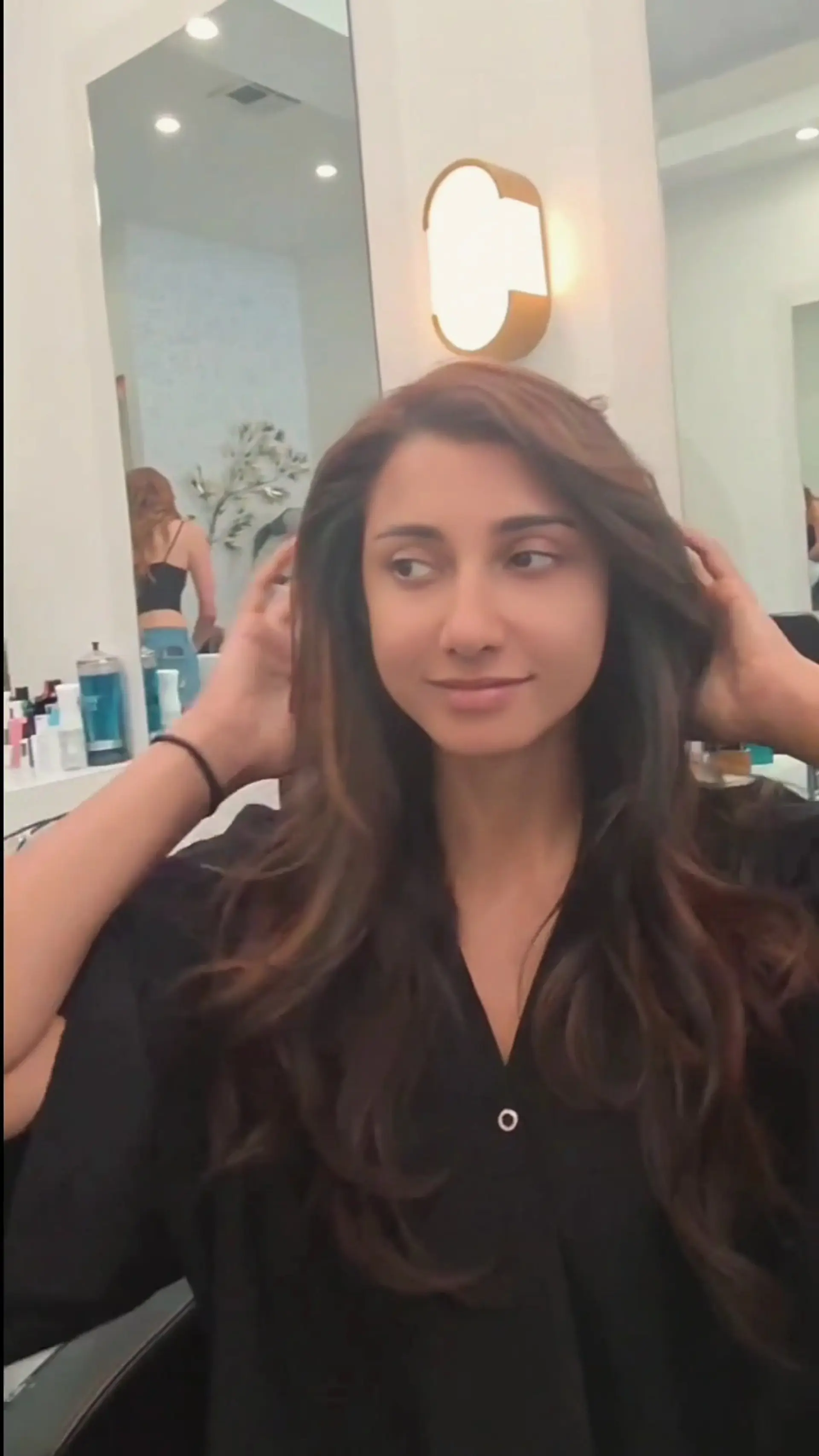 Long dark brown hair cut in soft layers with warm dimensional highlights and a bouncy blowout. 1