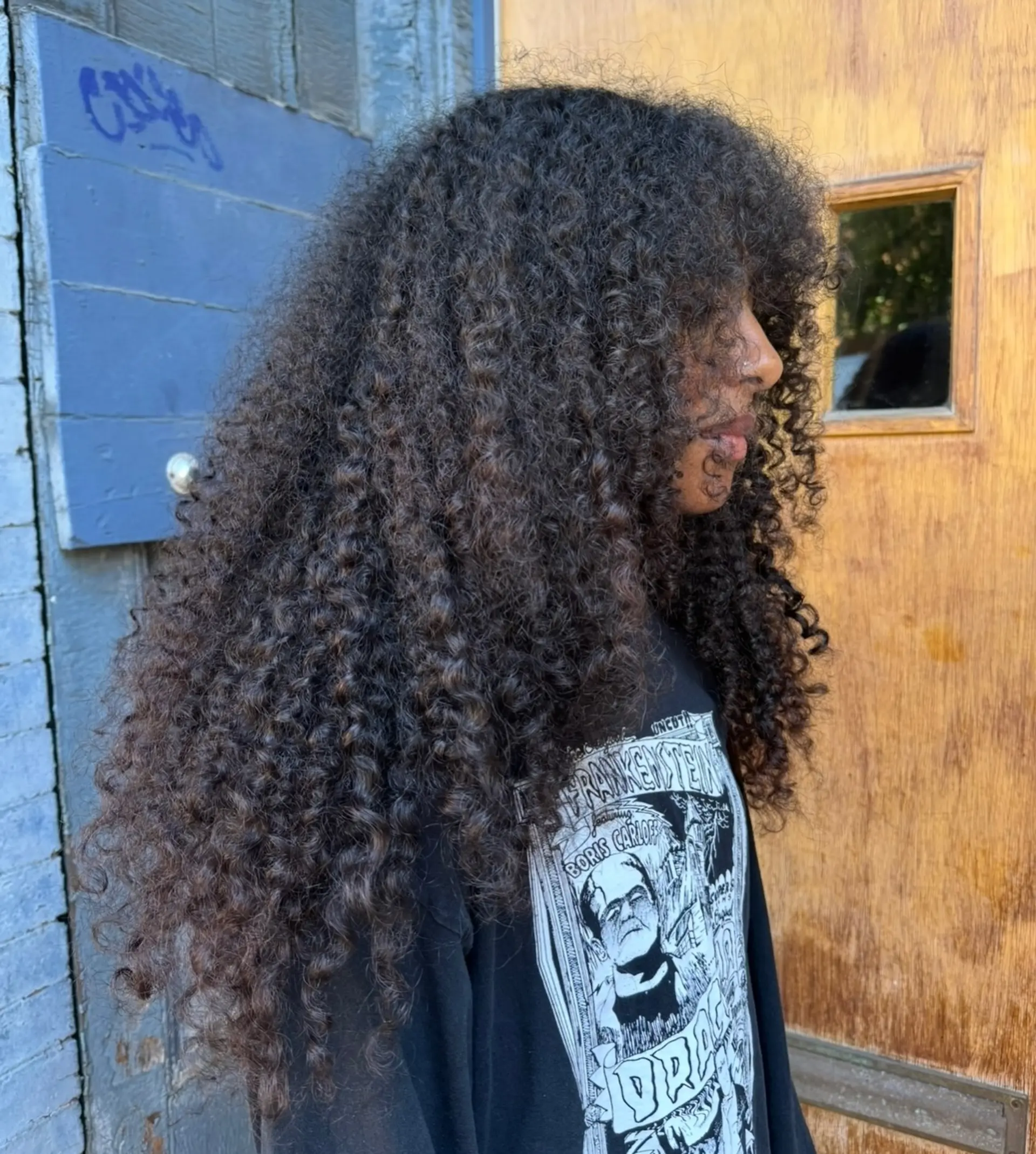 Voluminous long tight curls cut into a layered shag with full curly bangs. 1