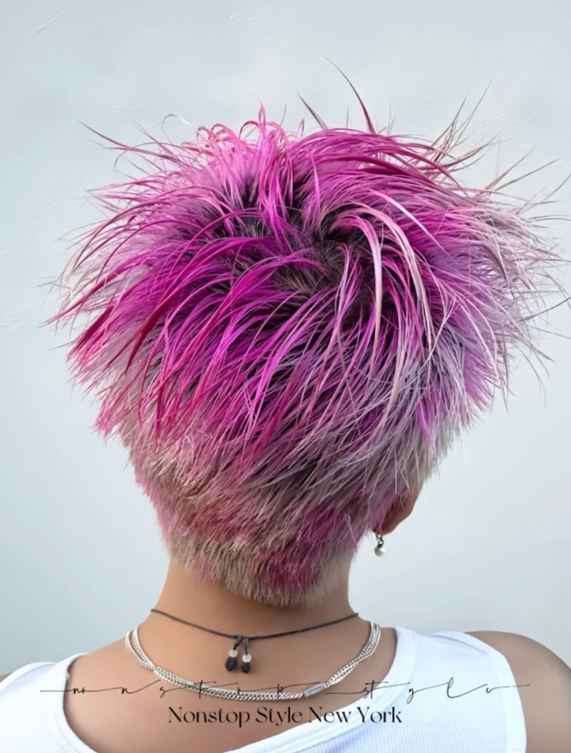 A short pixie cut with an undercut, featuring spiky, textured layers in vivid pink and platinum blonde. 1