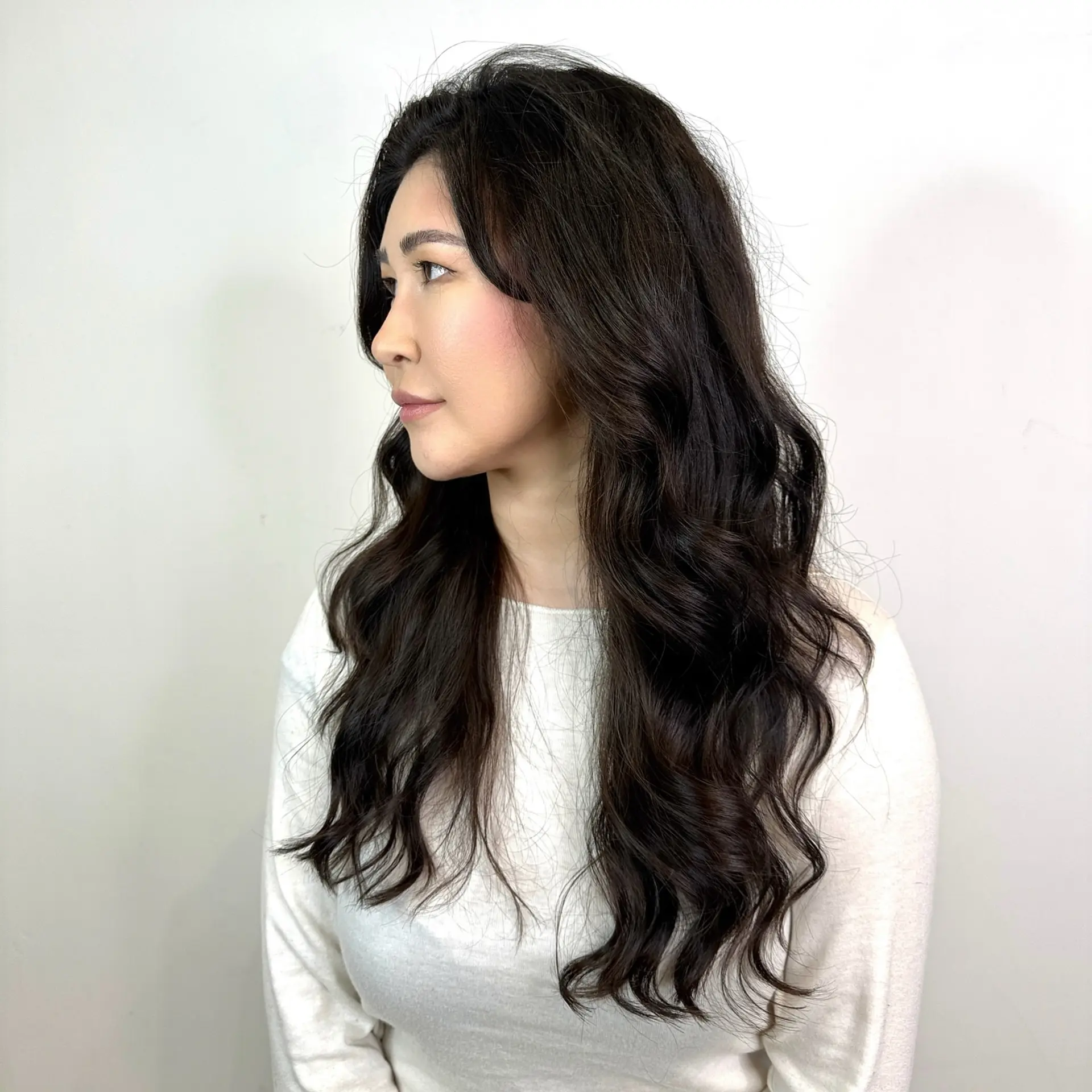 Long, flowing dark hair styled with soft, loose body waves that cascade past the shoulders with voluminous texture. 1